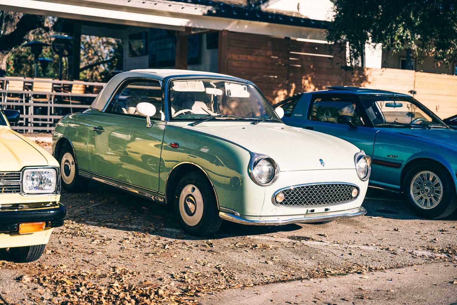Vintage mint green classic car with rounded design parked alongside modern vehicles.
