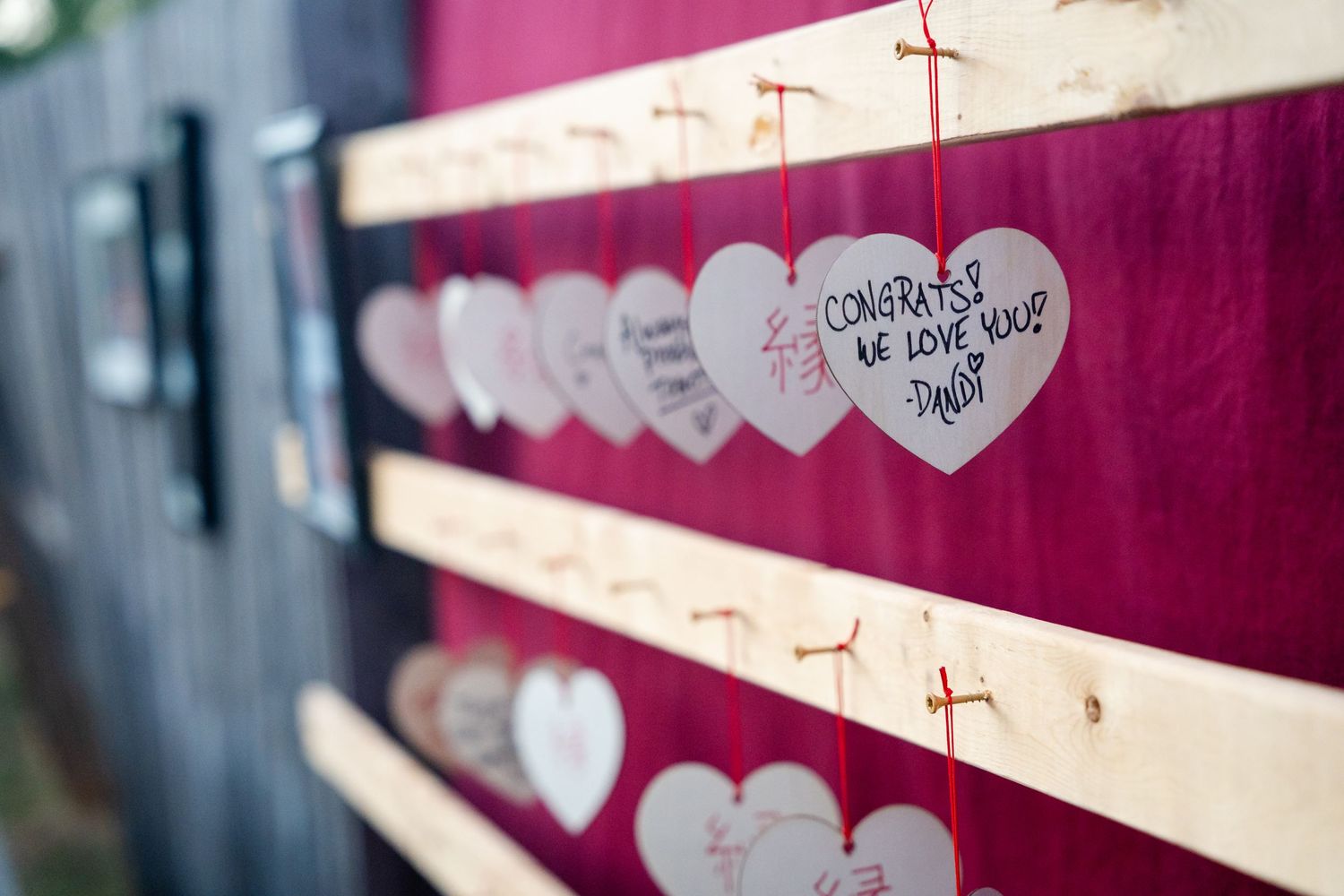 Row of paper hearts with handwritten messages displayed against striped background.