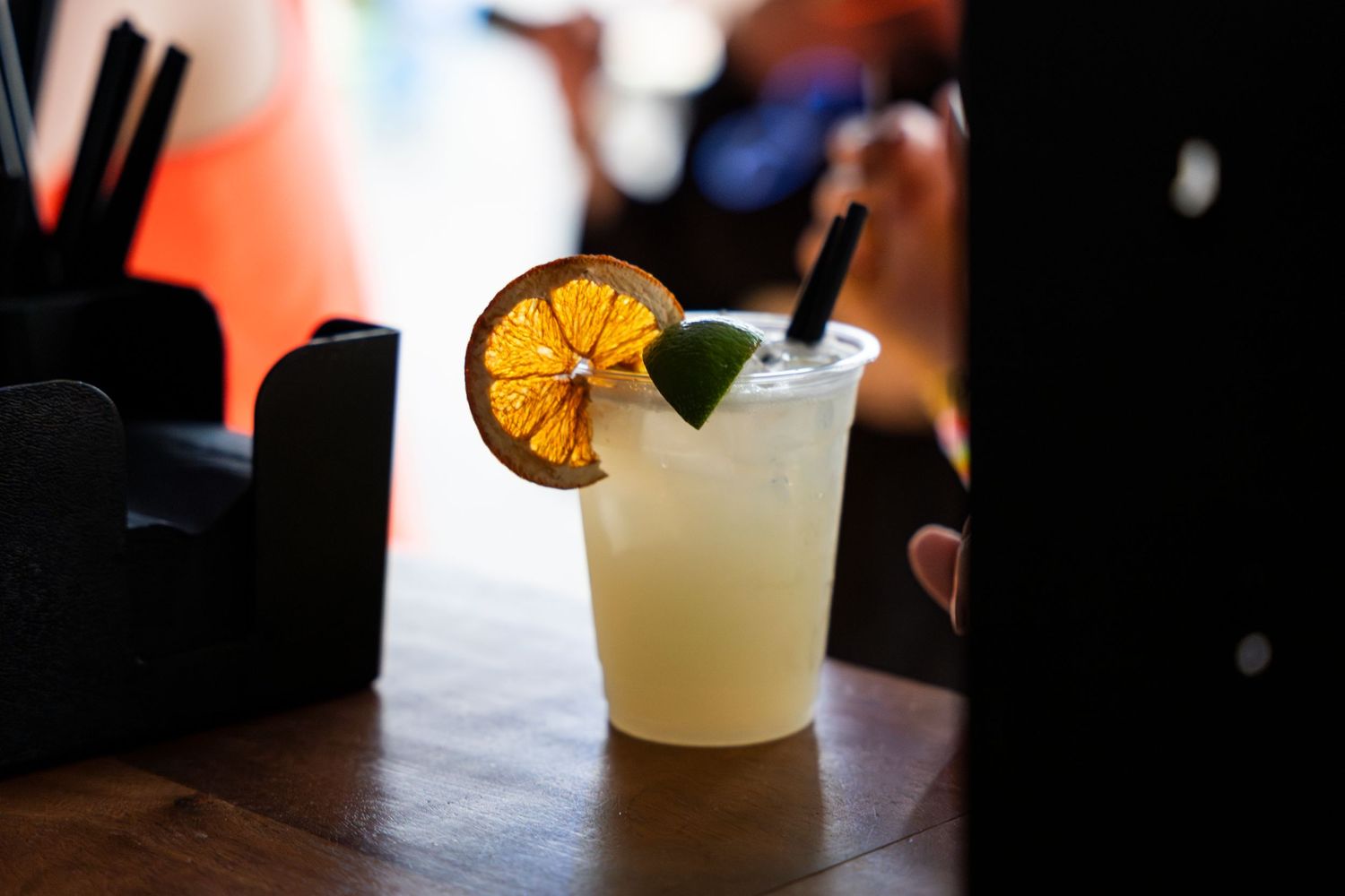 Six different cocktails with citrus garnishes line up on a dimly lit bar, showcasing various glassware styles and presentations.