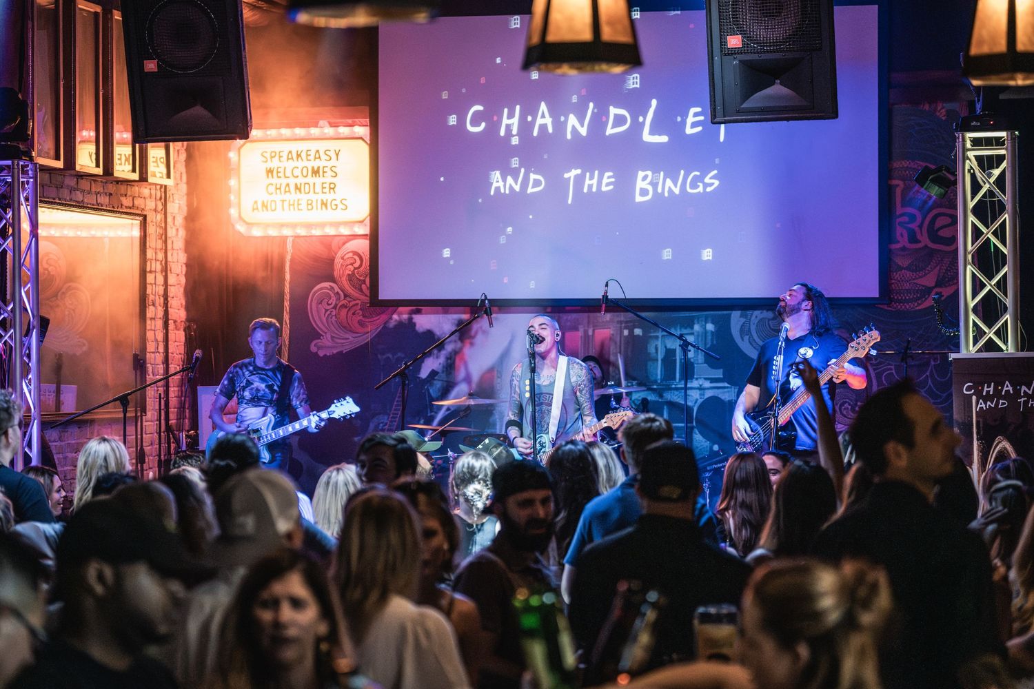 Live band plays energetic show under Chandler projection with packed audience dancing.