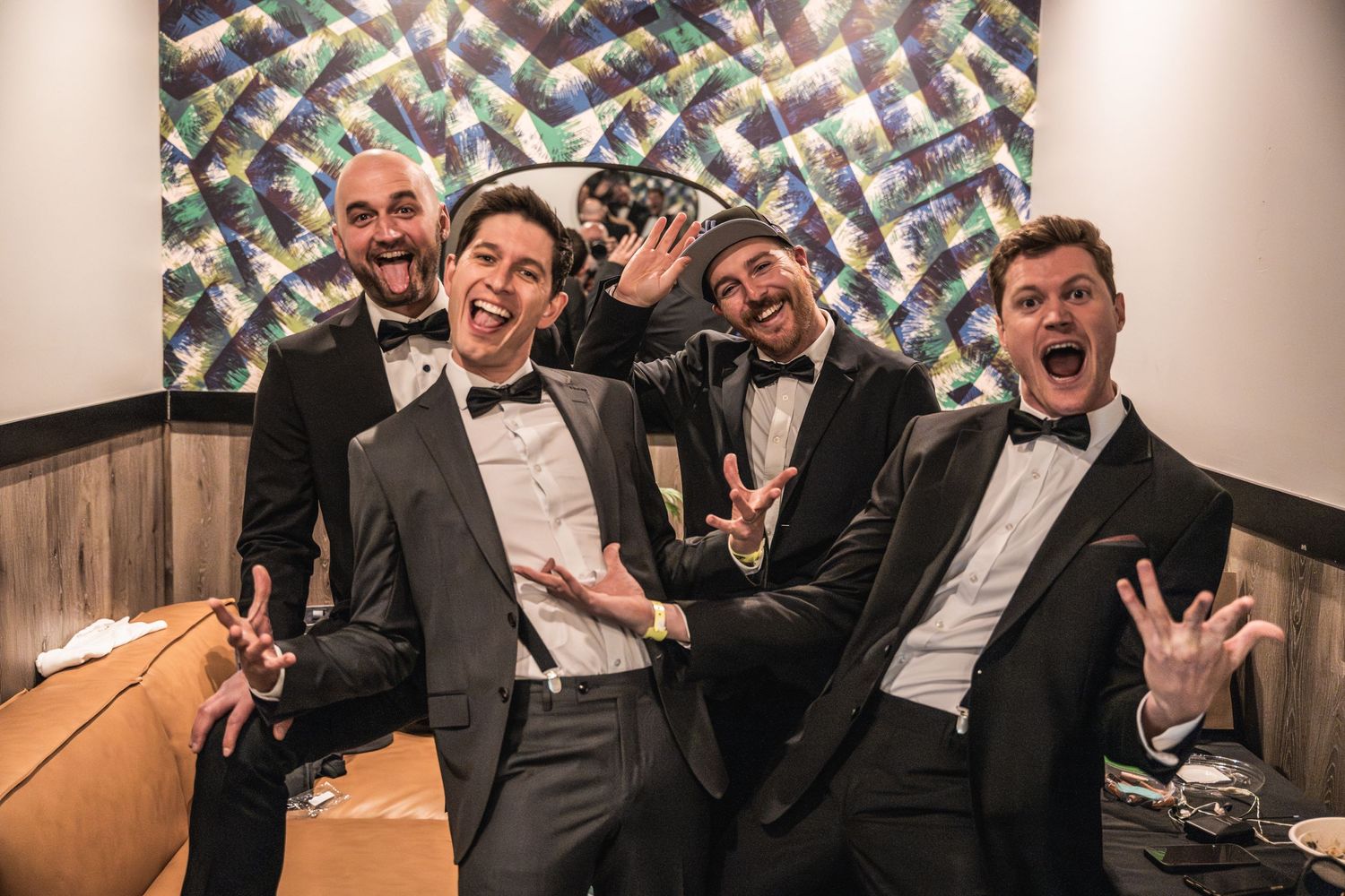 Musicians in tuxedos pose playfully backstage before a performance.