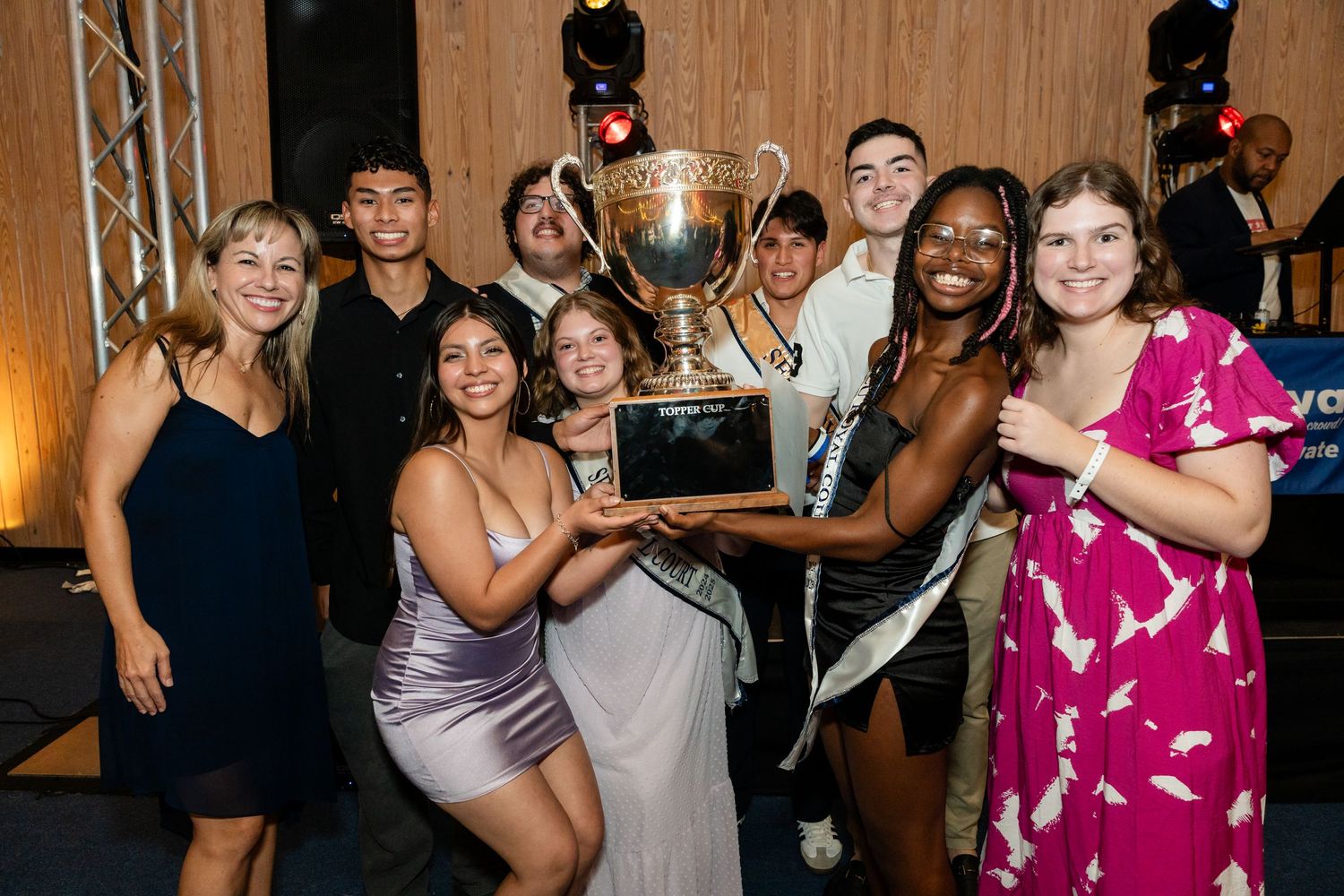 A group poses with a trophy at an indoor celebration event.