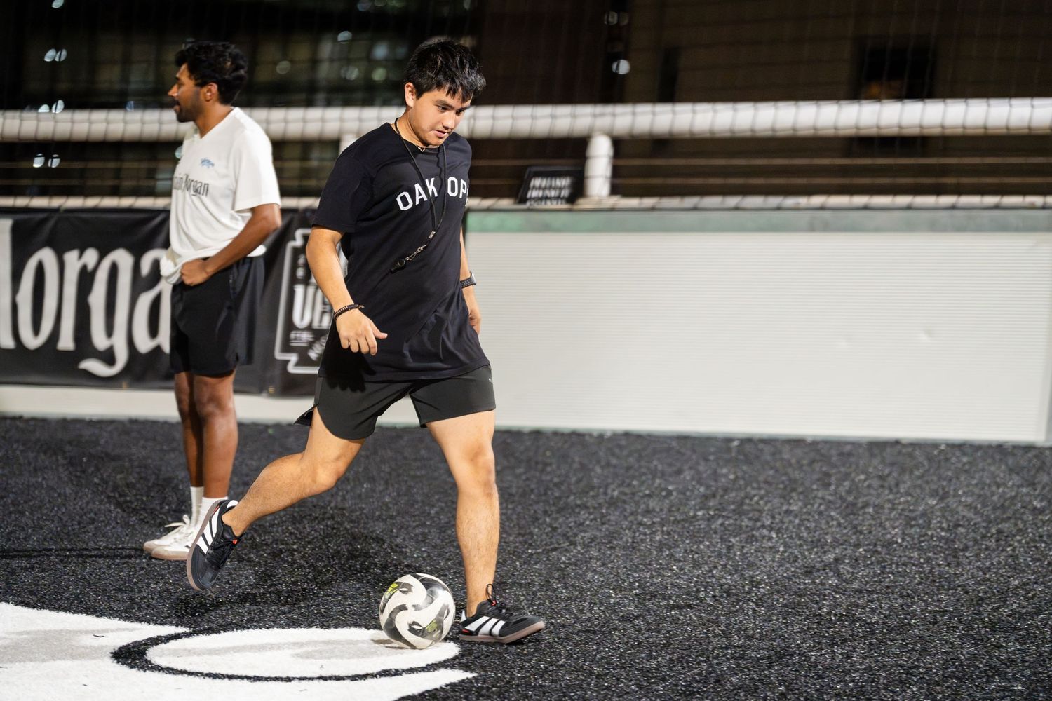 Soccer players practicing on an indoor turf field with dark artificial grass.