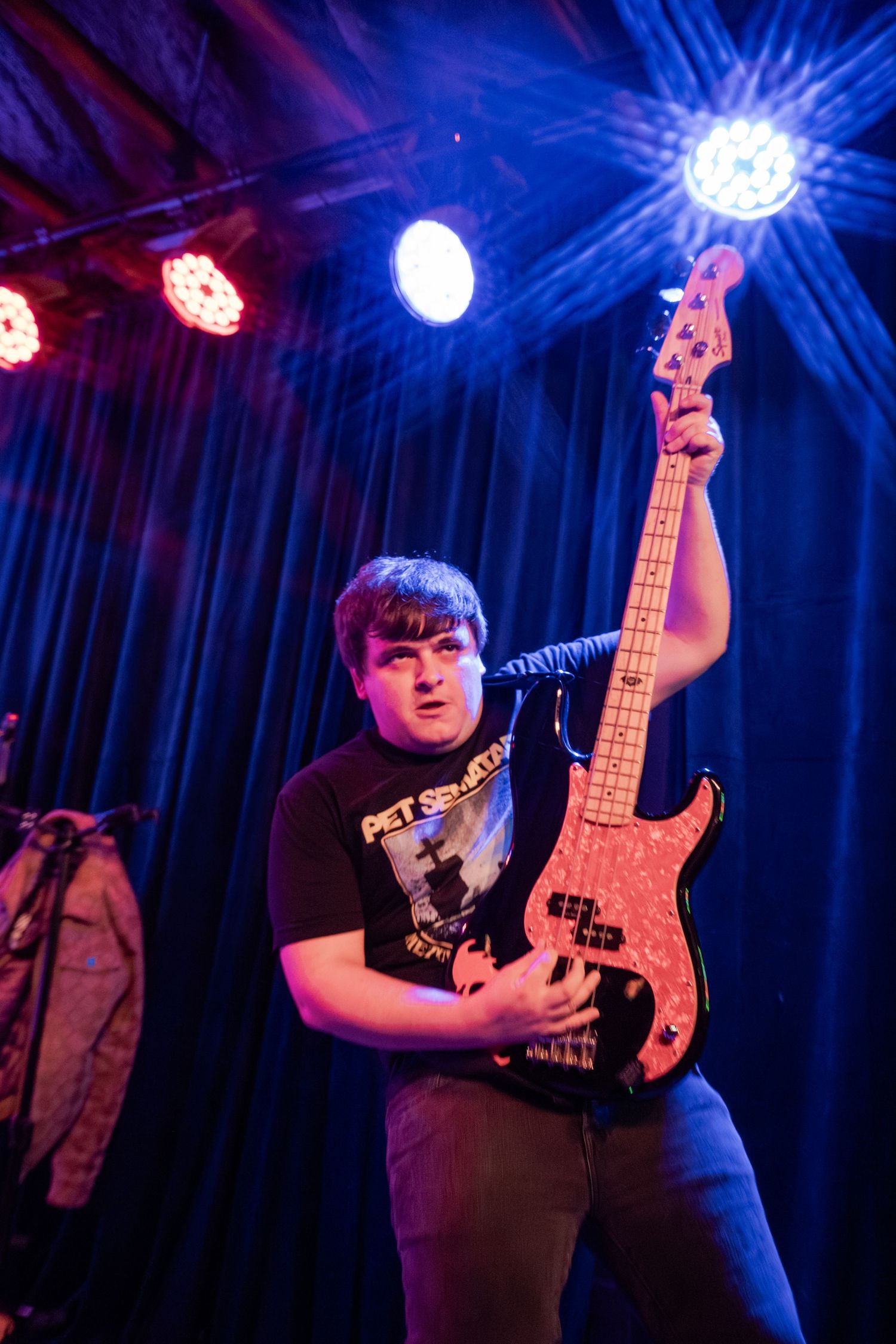 A guitarist performs on stage under dramatic blue lighting at a live music venue.