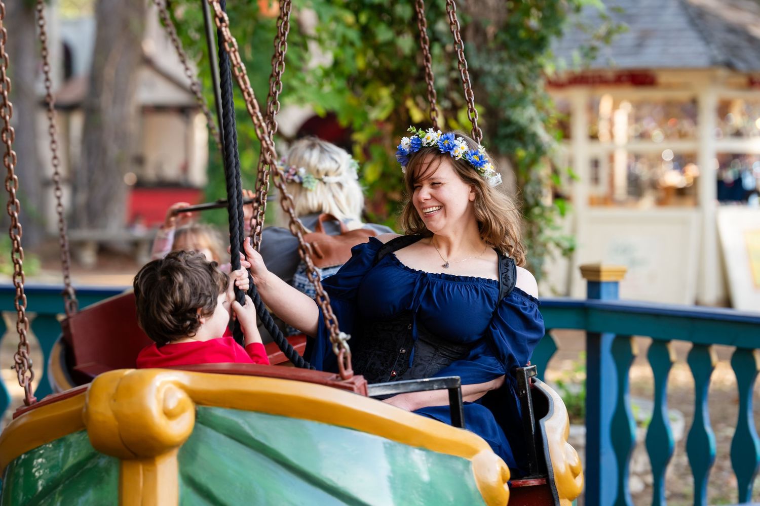 People enjoying a vintage carousel ride at an amusement park on a sunny day.