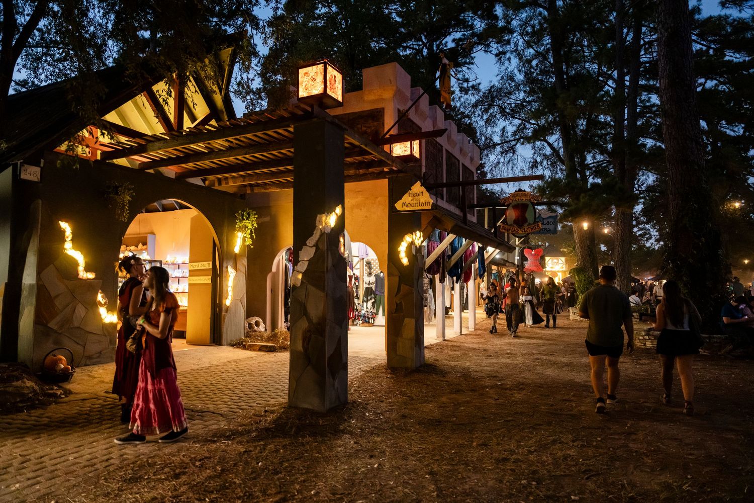 People gather at dusk around illuminated outdoor lanterns during a festive evening event.