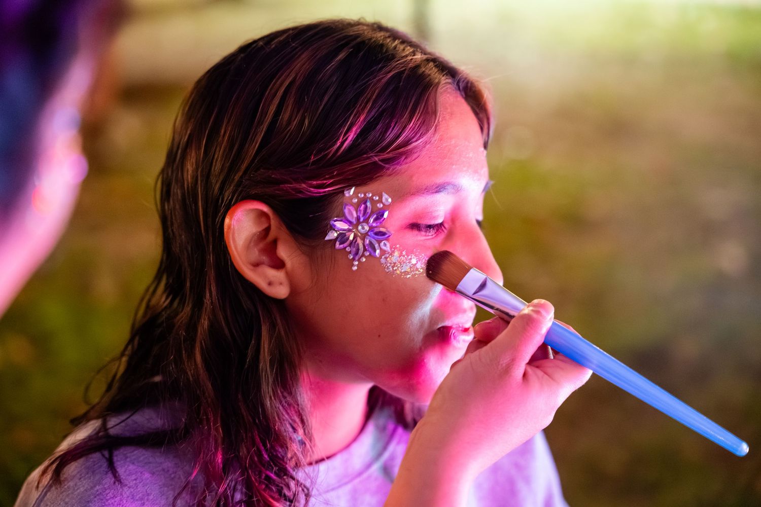 A person blows bubbles with a bubble wand in a series of sequential shots with pink and green lighting effects.