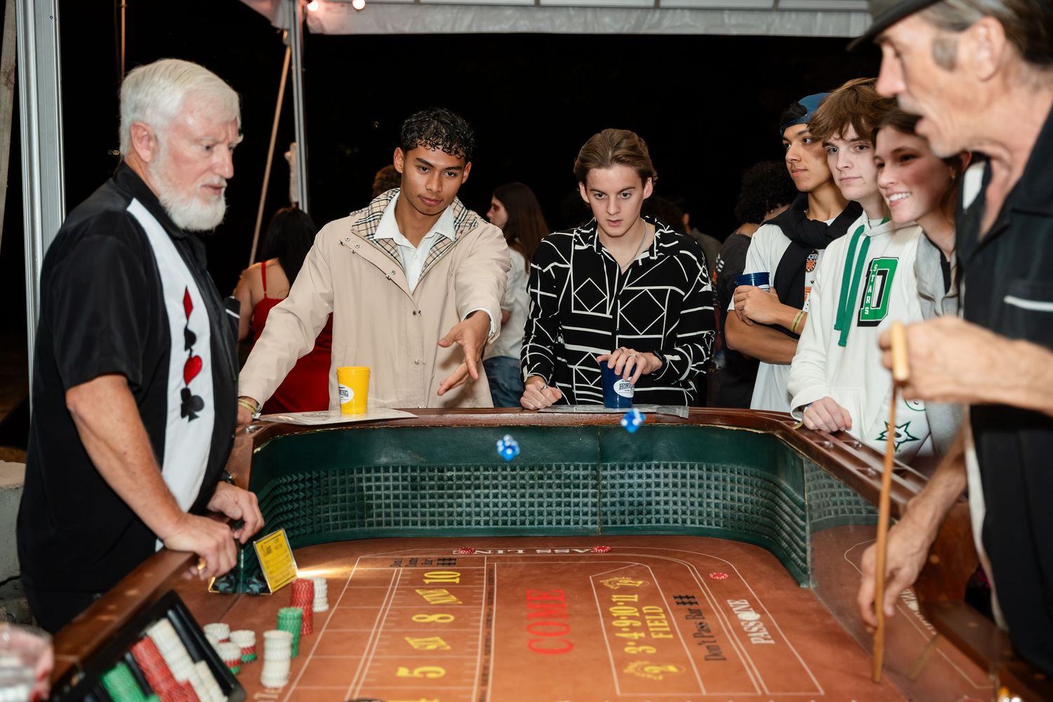 People gather around a shuffleboard table during a competitive game at a social venue.