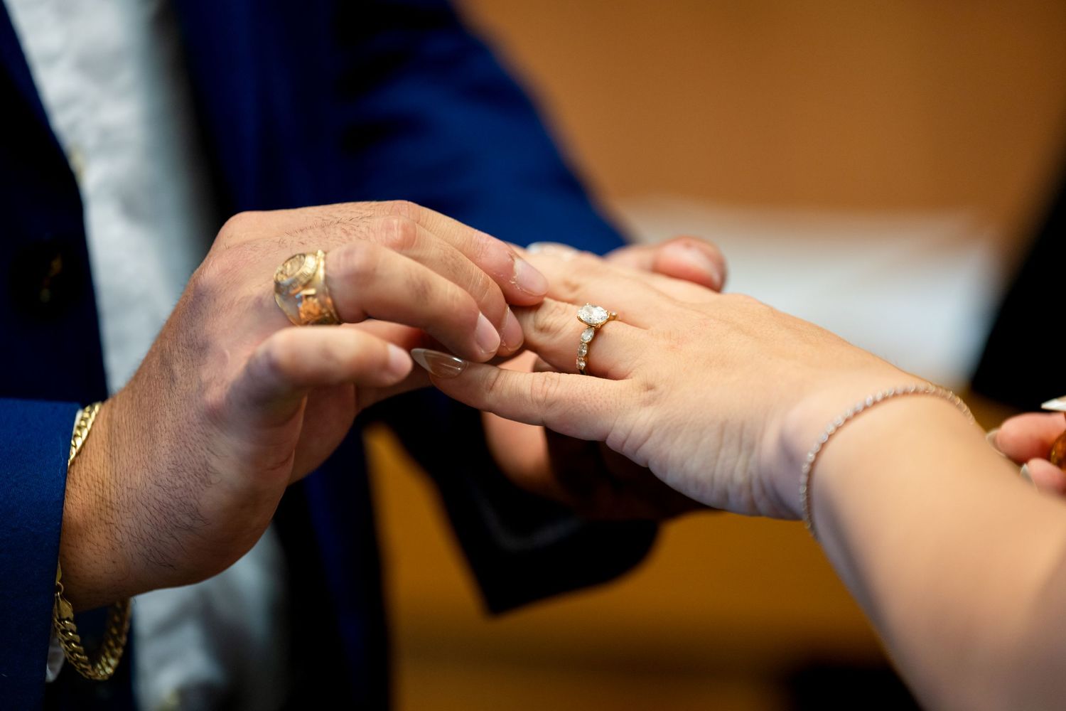 A close-up shot of hands exchanging wedding rings during a marriage ceremony.