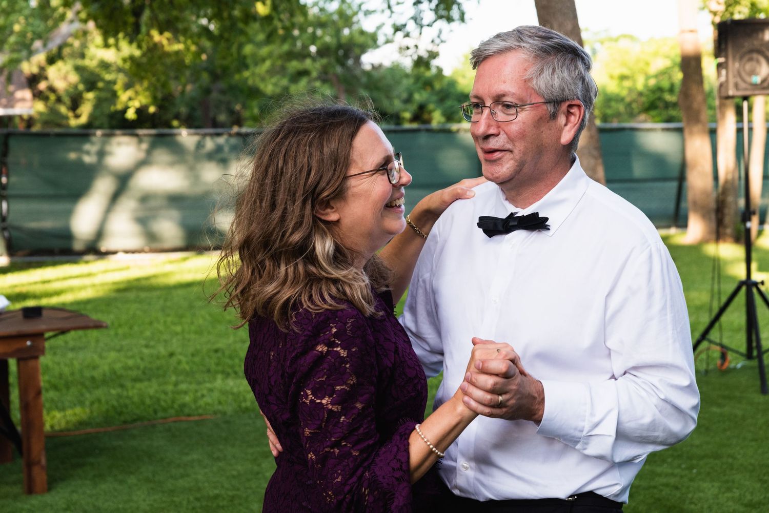 Couple dancing and laughing together at an outdoor garden reception.