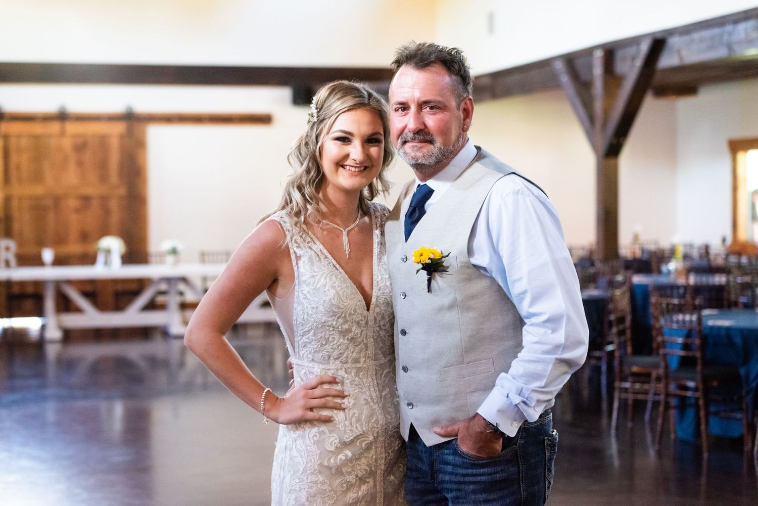 A lovely couple poses in a rustic reception venue with wooden beams and elegant decor.