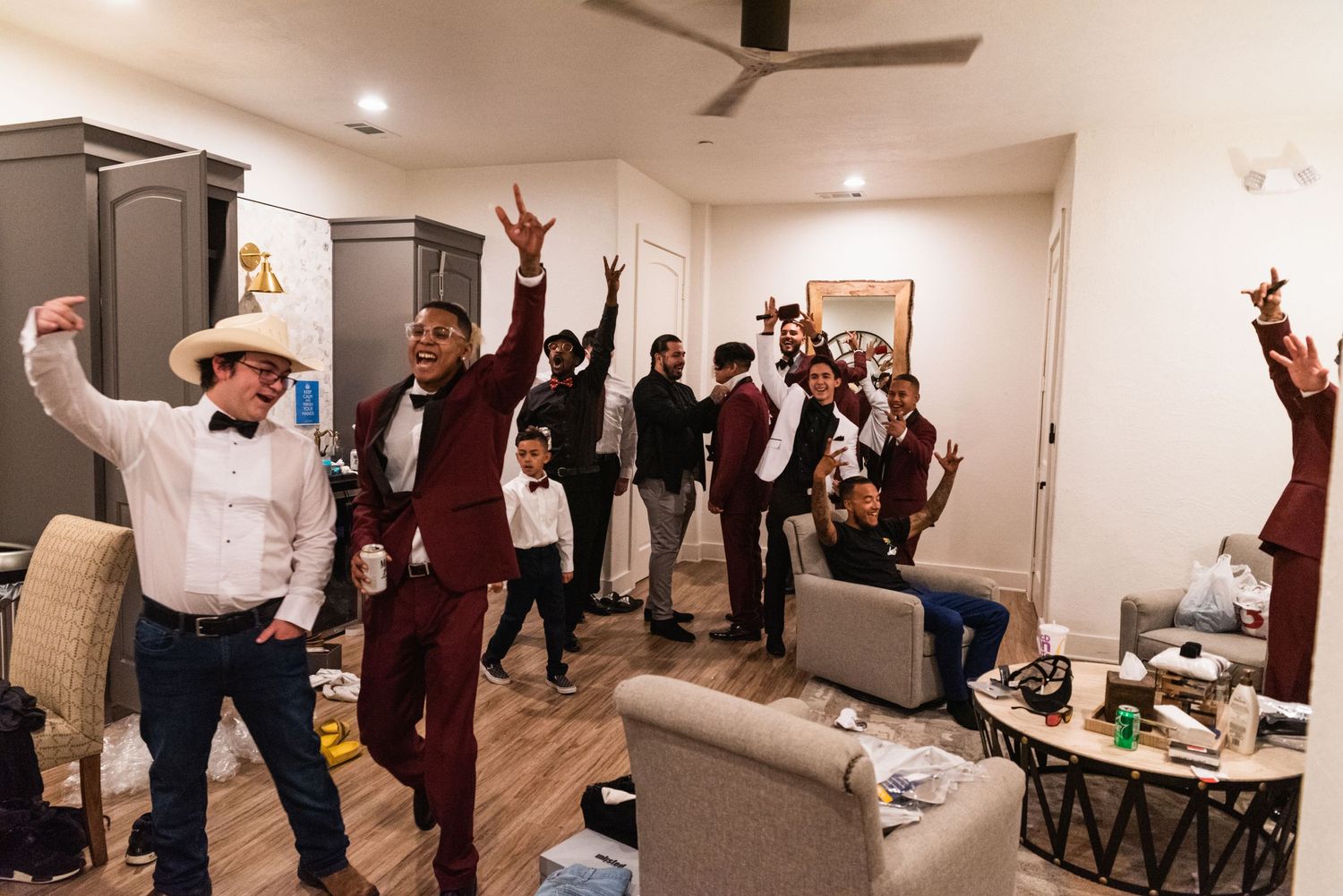 Wedding party members celebrate enthusiastically in a living room setting.