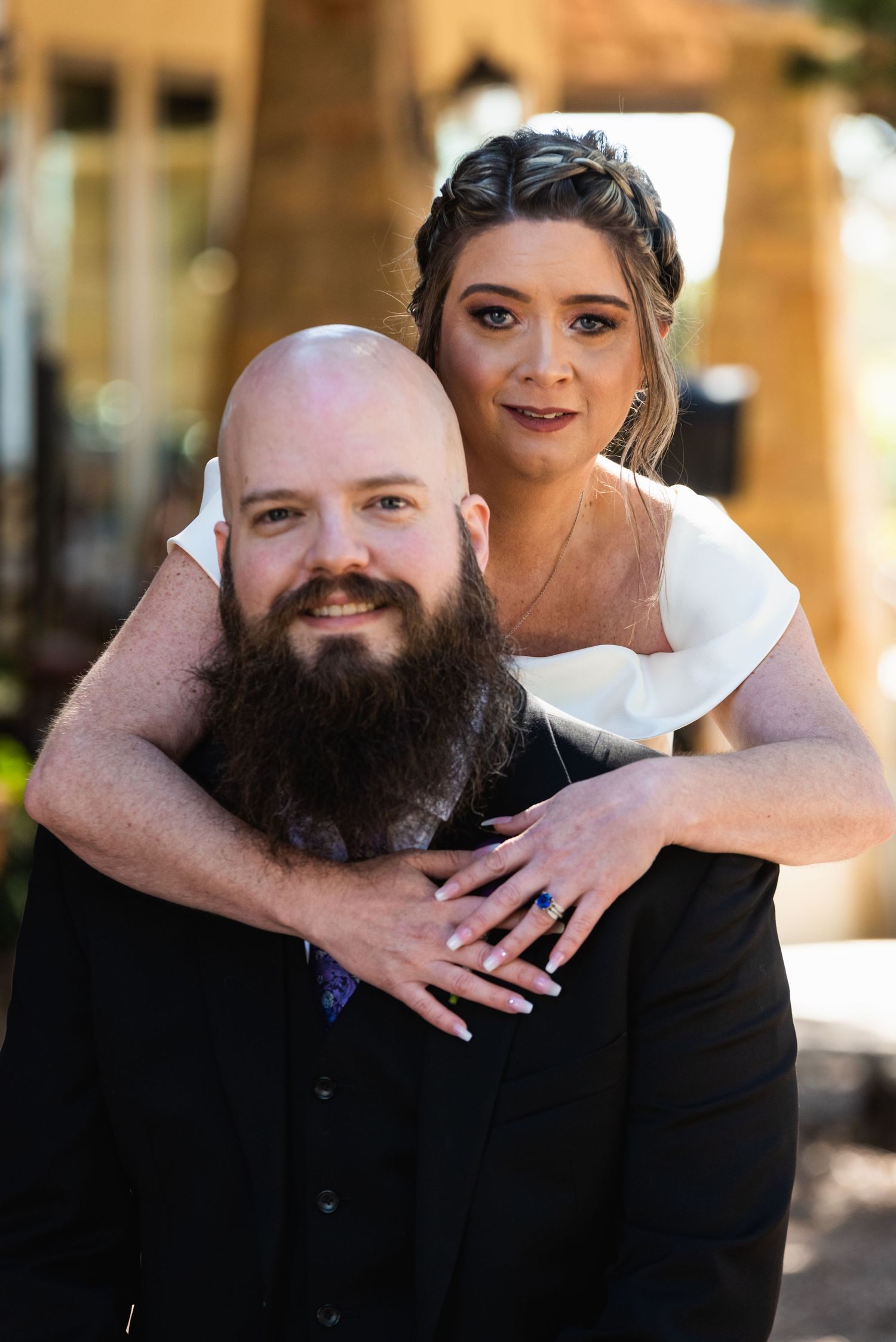 A couple in wedding attire pose together for a portrait in warm lighting.