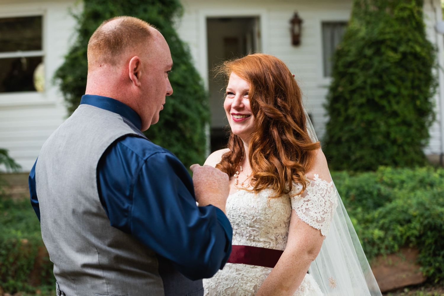 A tender wedding moment between a bride and groom sharing laughter in front of their venue.