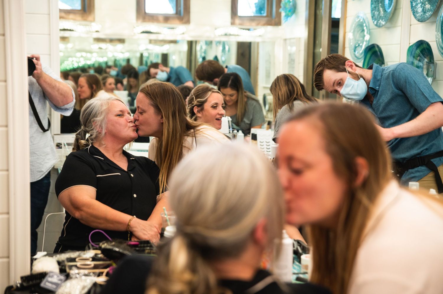 People gathered in a bright room with mirrors during a social event.
