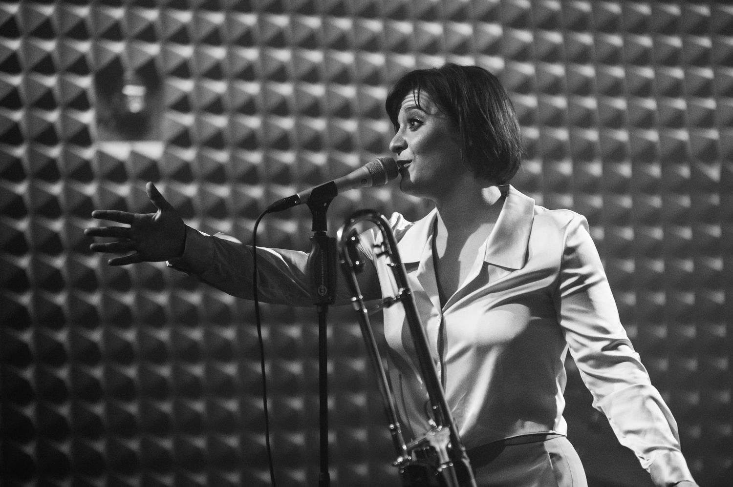 A black and white photo captures an energetic singing performance against a textured backdrop.
