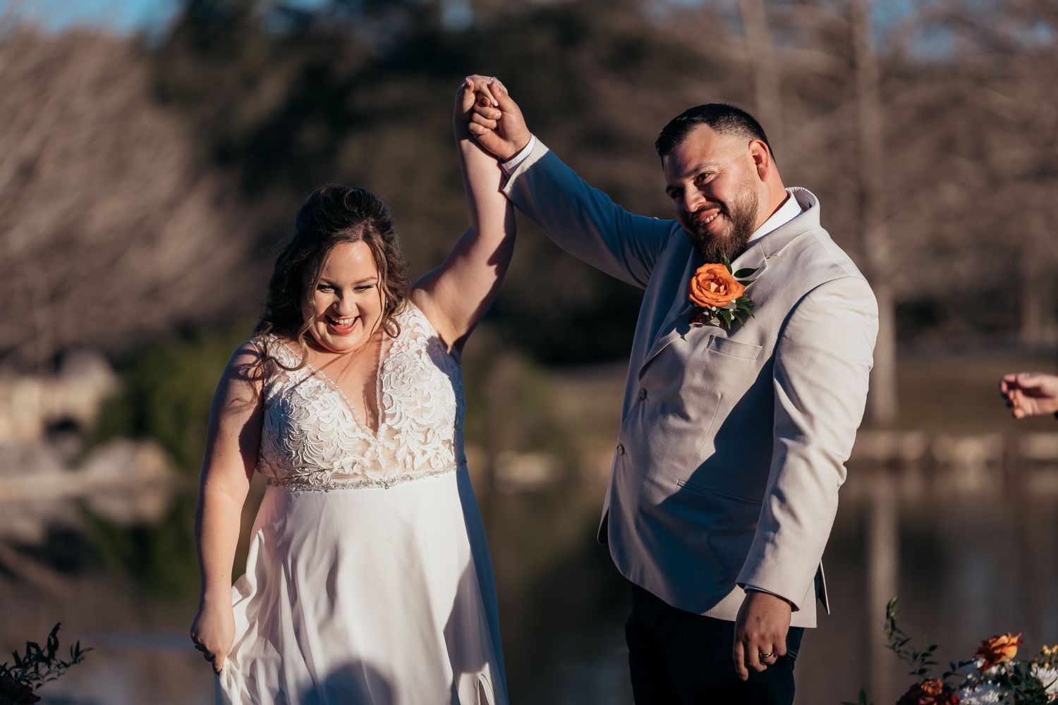A joyful celebration moment during a lakeside wedding with autumn colors in the background.