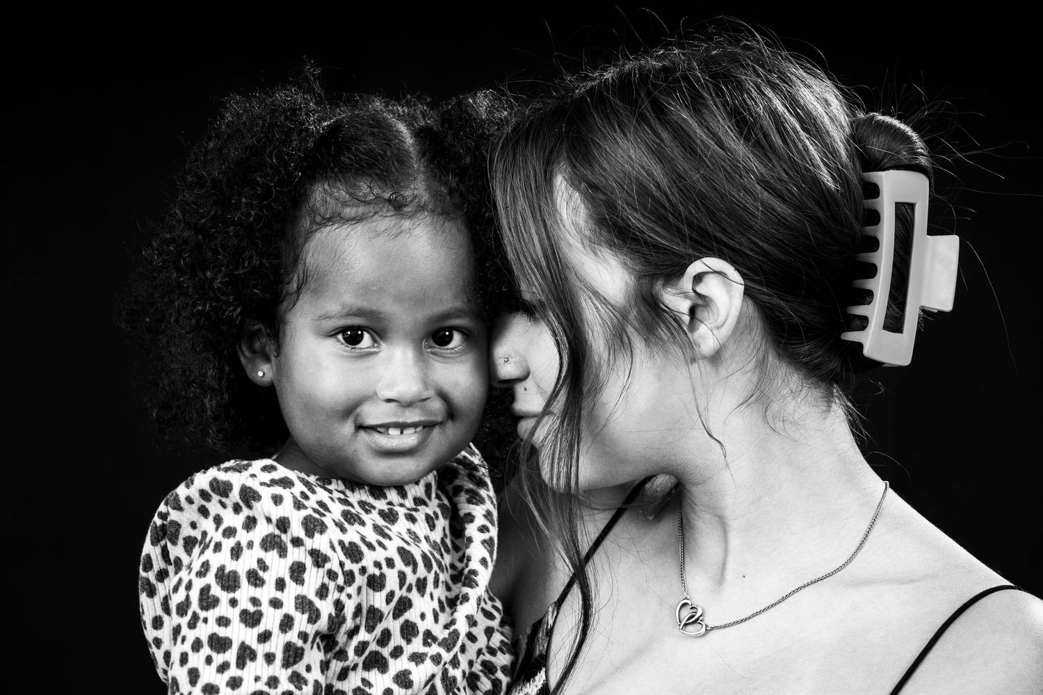Intimate black and white portrait of two people sharing a close moment.