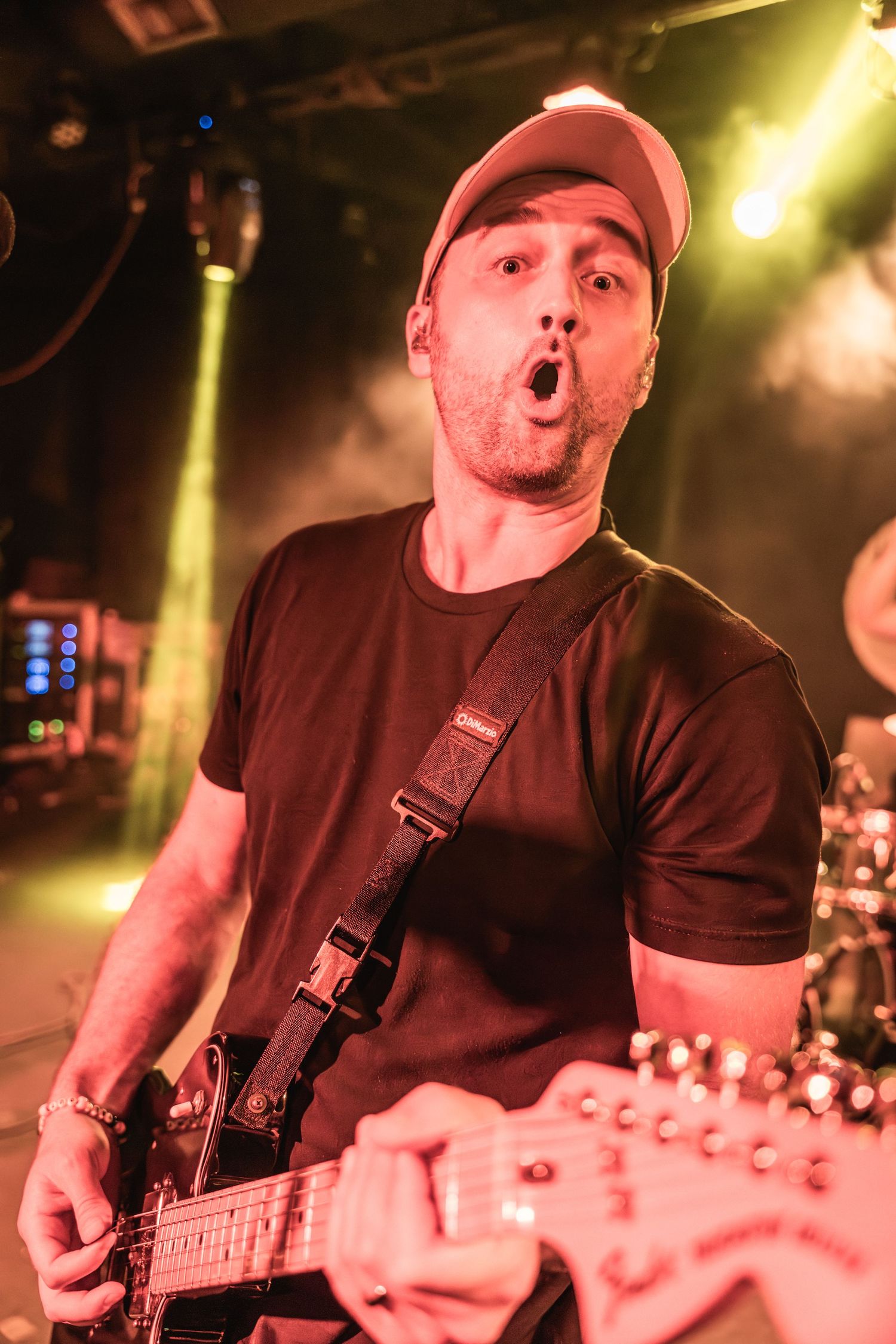 Musician plays guitar with intense expression under warm stage lighting.