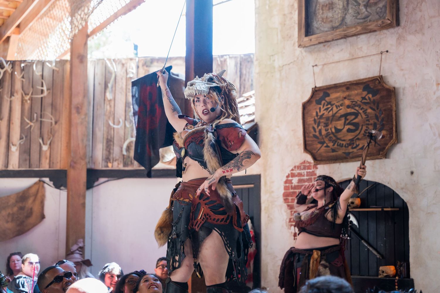 Performer entertains crowd from elevated stage at renaissance festival.