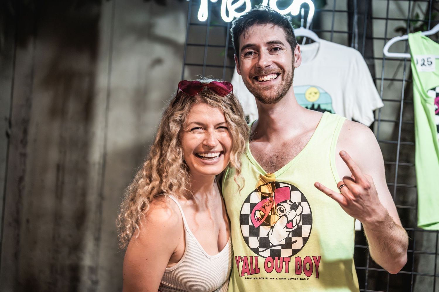 Festival attendees making rock gesture while posing in front of merchandise display.