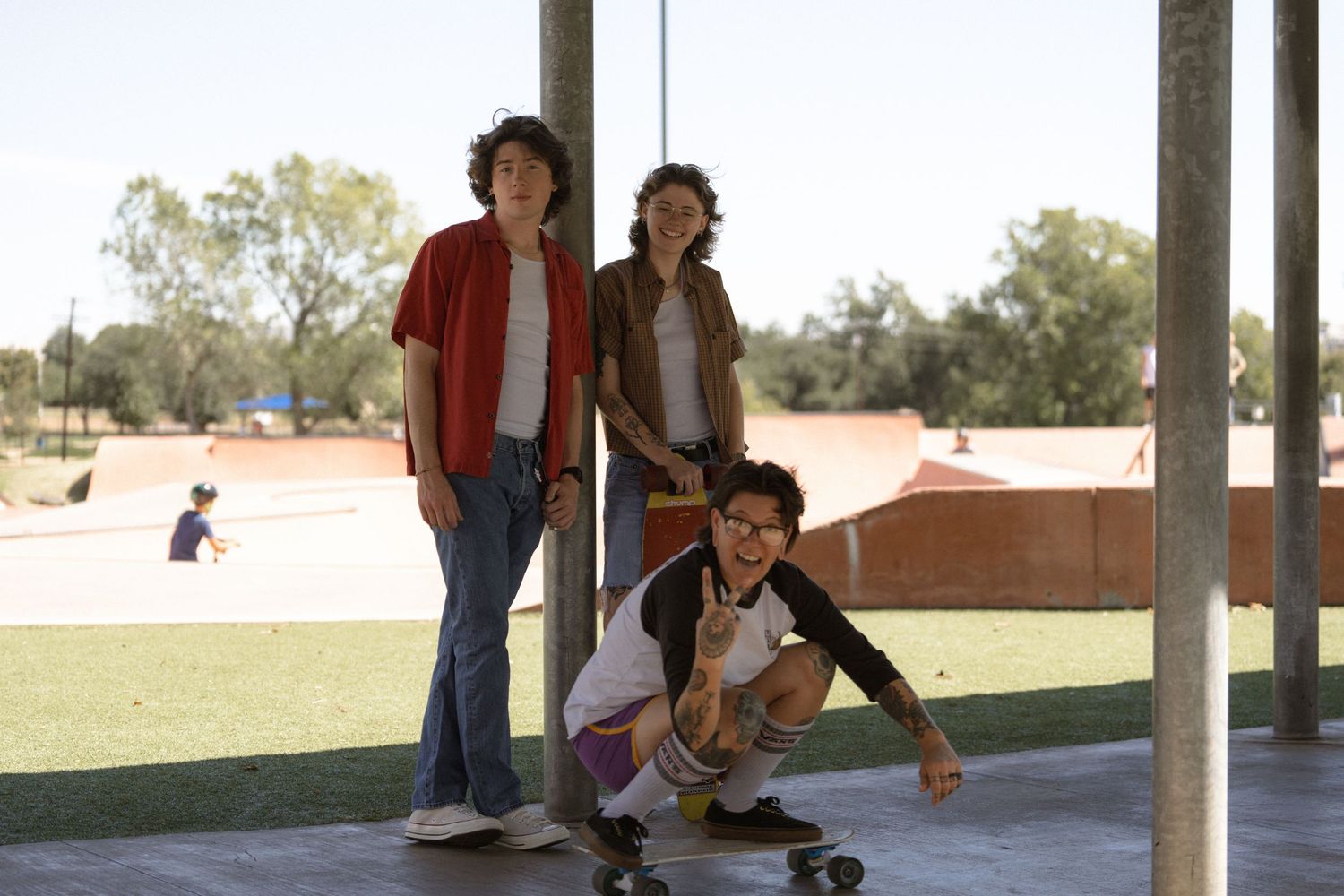 Friends hanging out at a skate park, with one person demonstrating skateboarding moves.