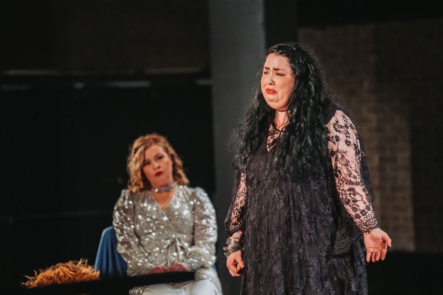 Two performers in contrasting dresses act out an emotional scene on stage.