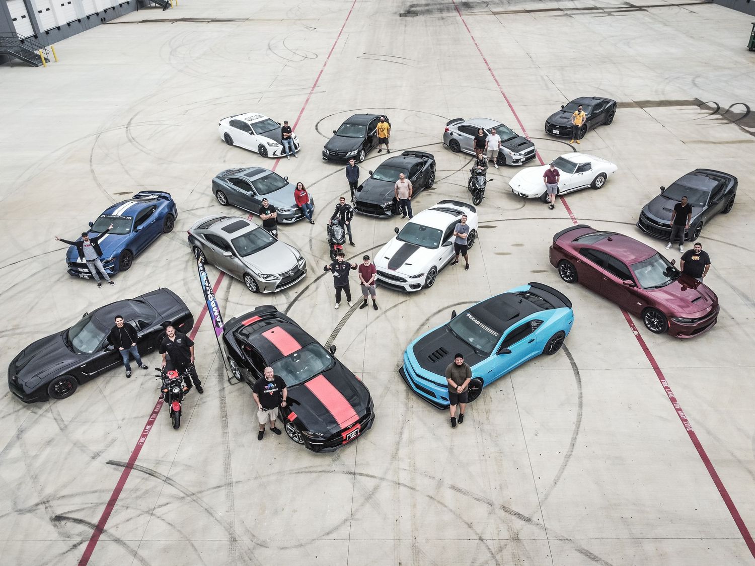 Overhead view of performance vehicles arranged in formation with tire marks on concrete.