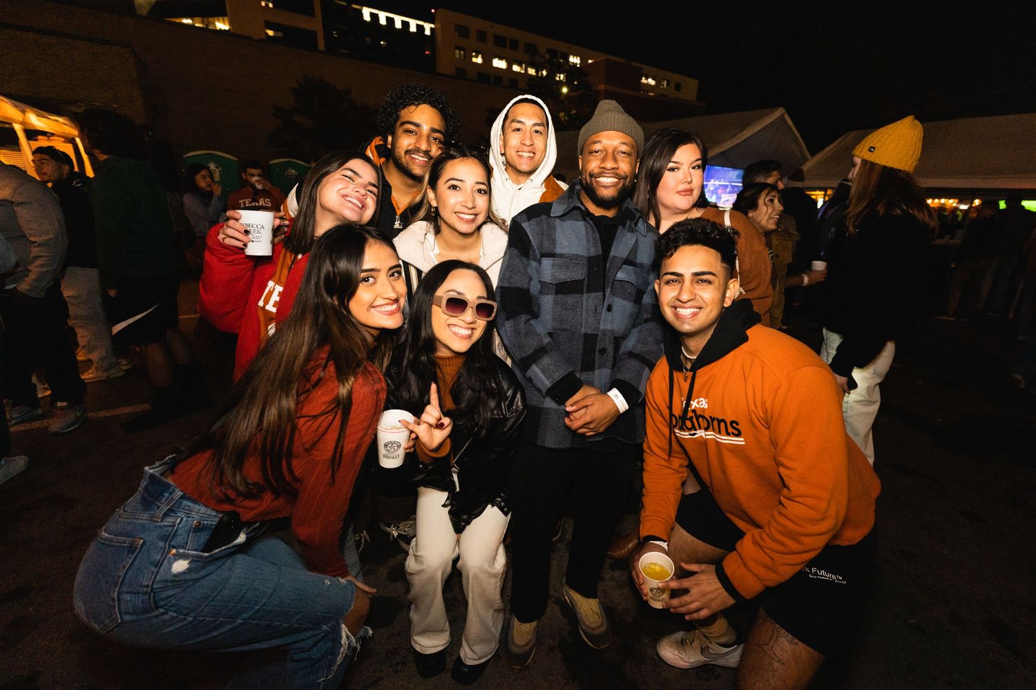 Diverse group of friends posing together for photo at nighttime outdoor event.