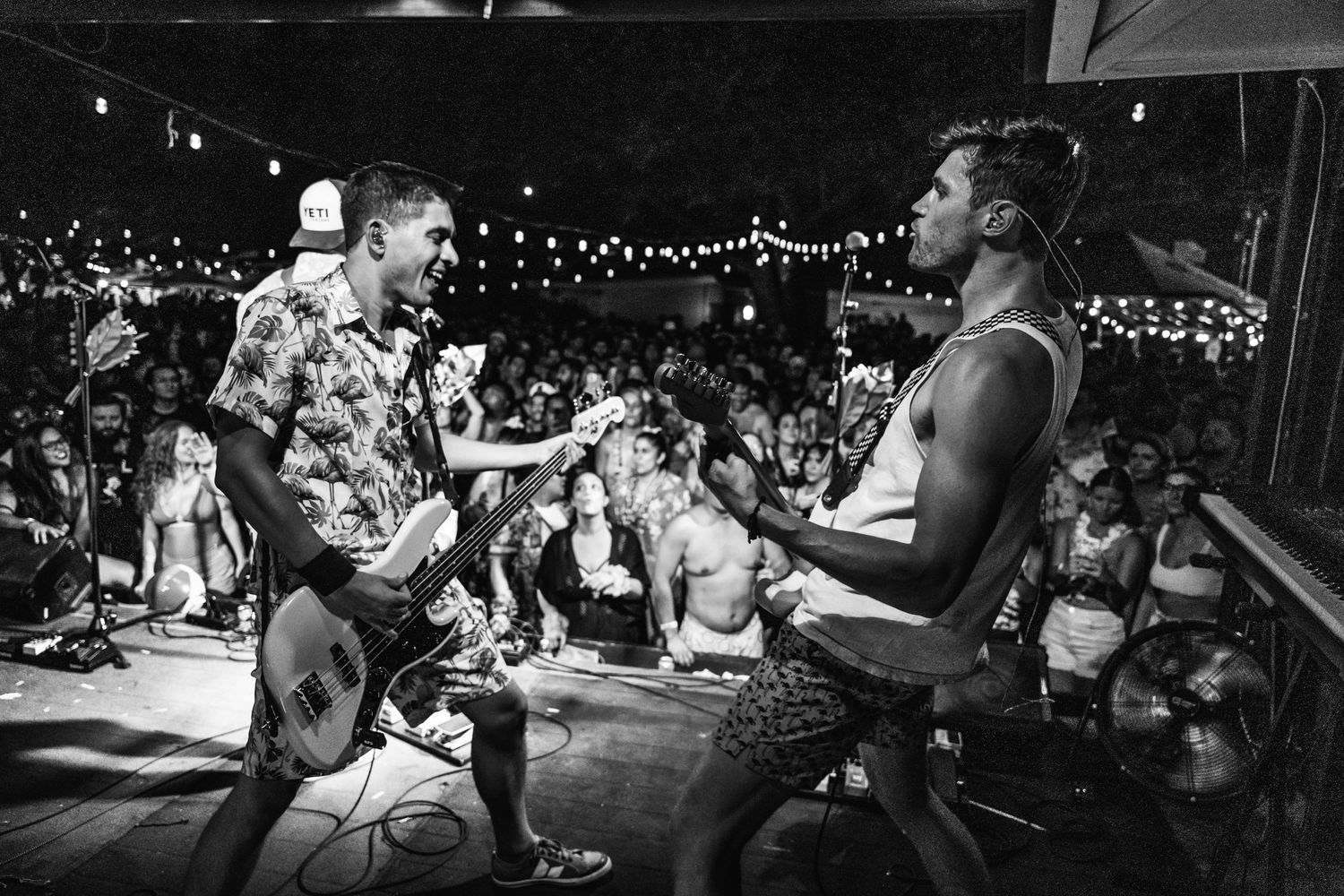 Black and white photo of musicians performing on stage at an energetic concert.
