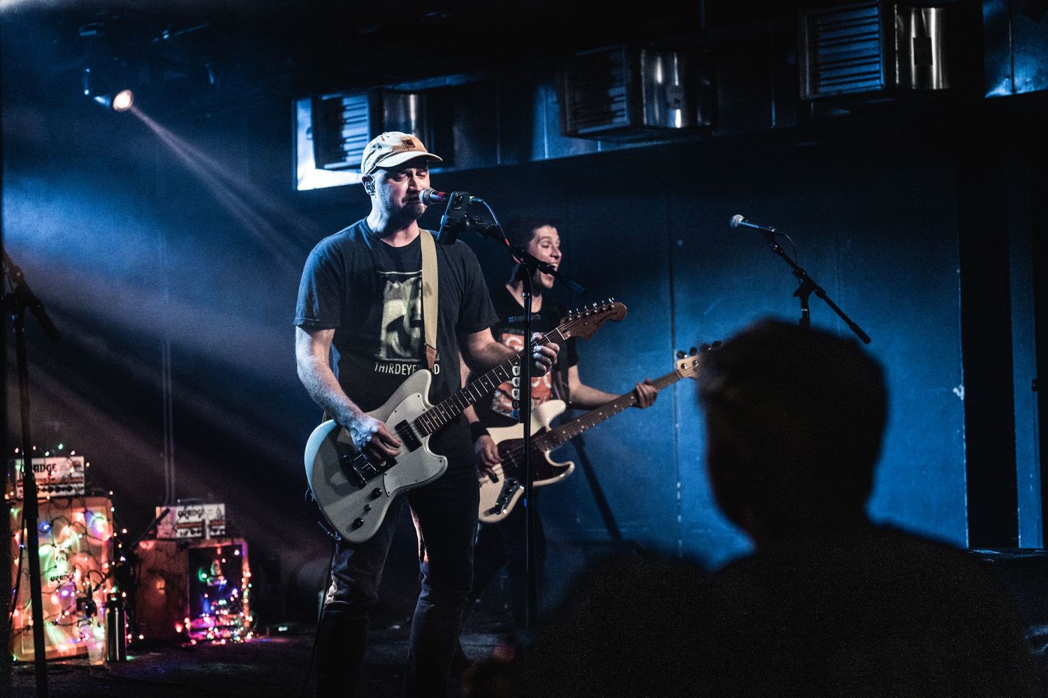 Band performing on stage with dramatic backlighting creating silhouettes.