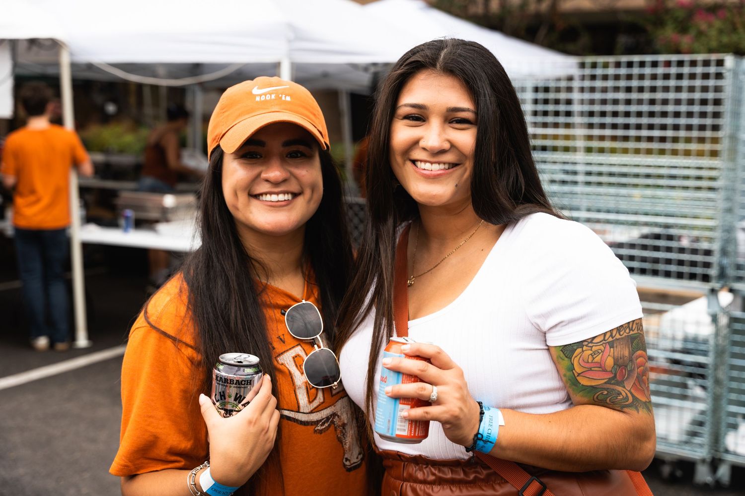 Two people in orange and white attire holding beverages at an outdoor gathering.