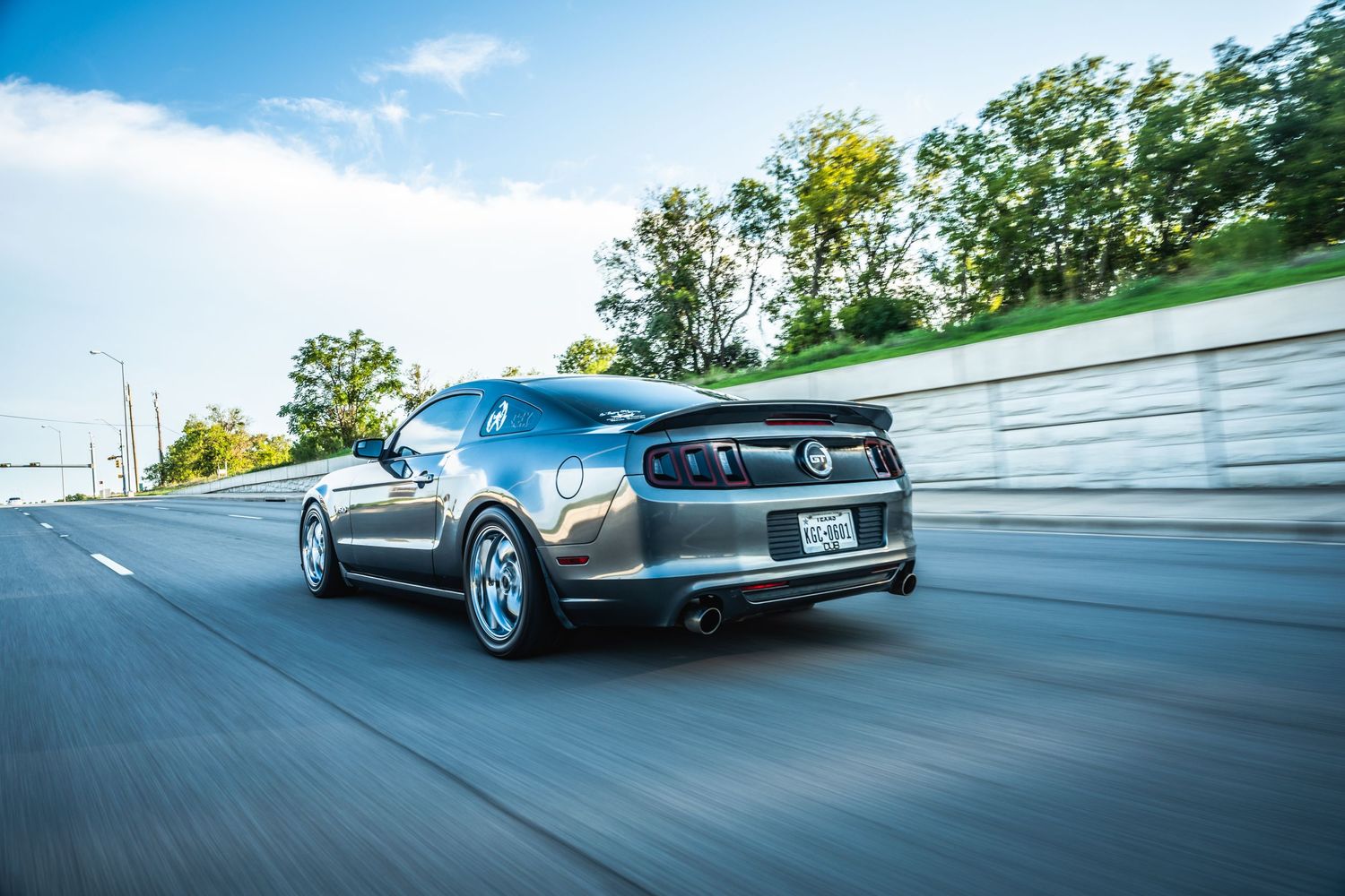 Gray performance Dodge Charger with custom wheels in dynamic highway driving shot.