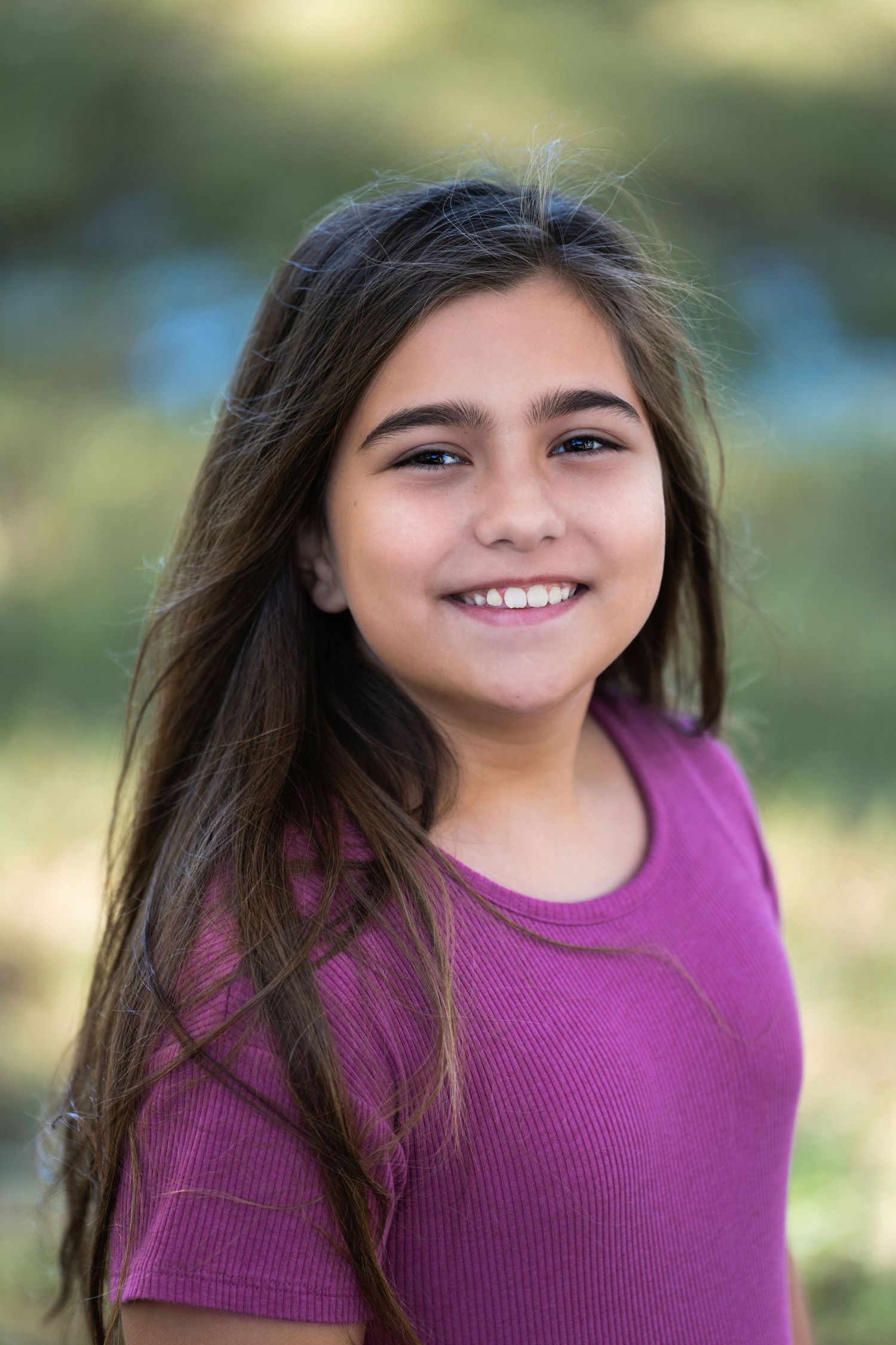 Outdoor portrait of young person in purple top with natural lighting.