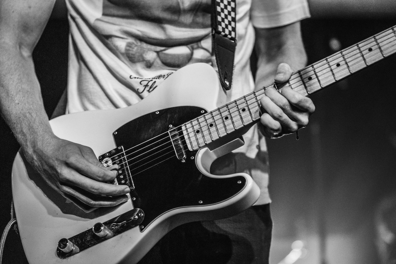 Close-up black and white shot of hands playing a Telecaster electric guitar.