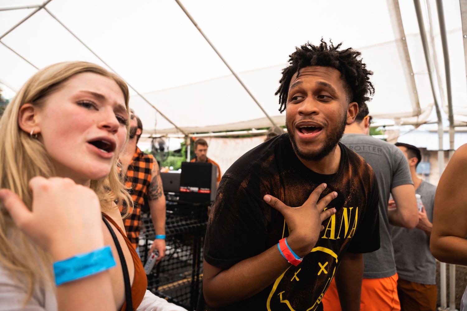 Energetic partygoers laughing and having animated conversations at an outdoor event.