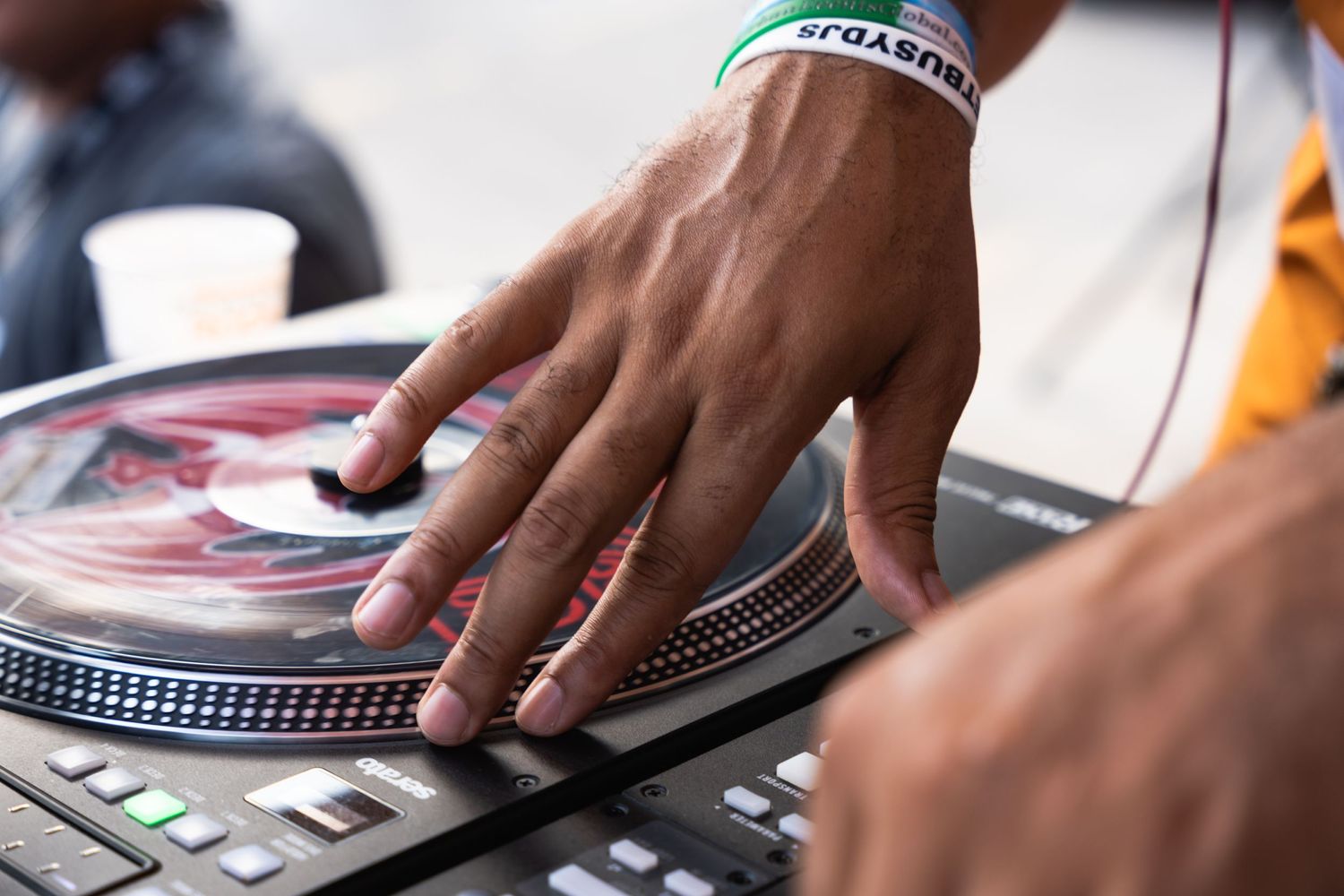 Close-up shot of hands operating DJ equipment with turntables.