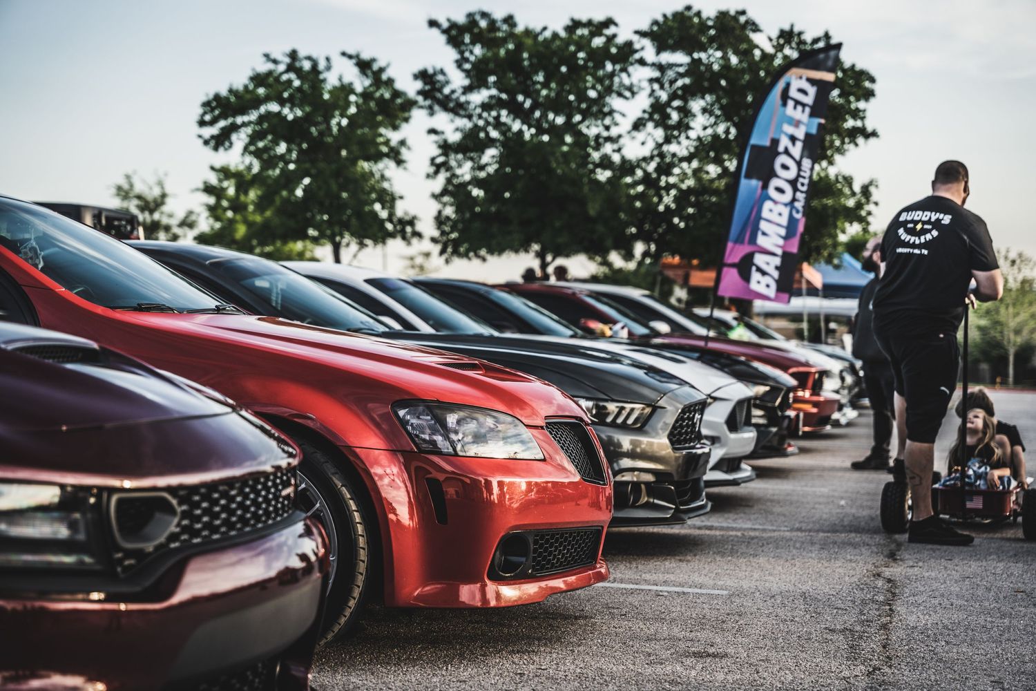 Row of customized sports cars parked at an outdoor automotive event.