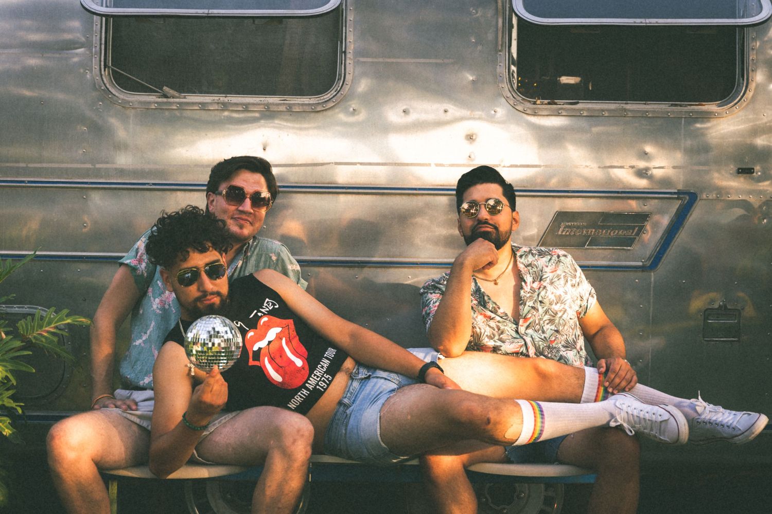 Three friends relaxing together on a vintage metallic surface outdoors on a sunny day.