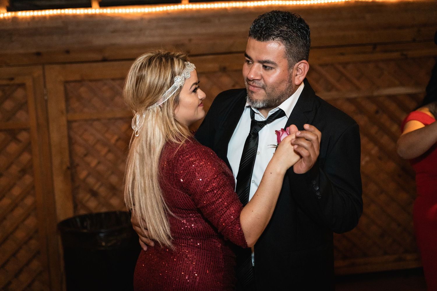 A couple shares a romantic dance moment, with one wearing a sparkly red dress.