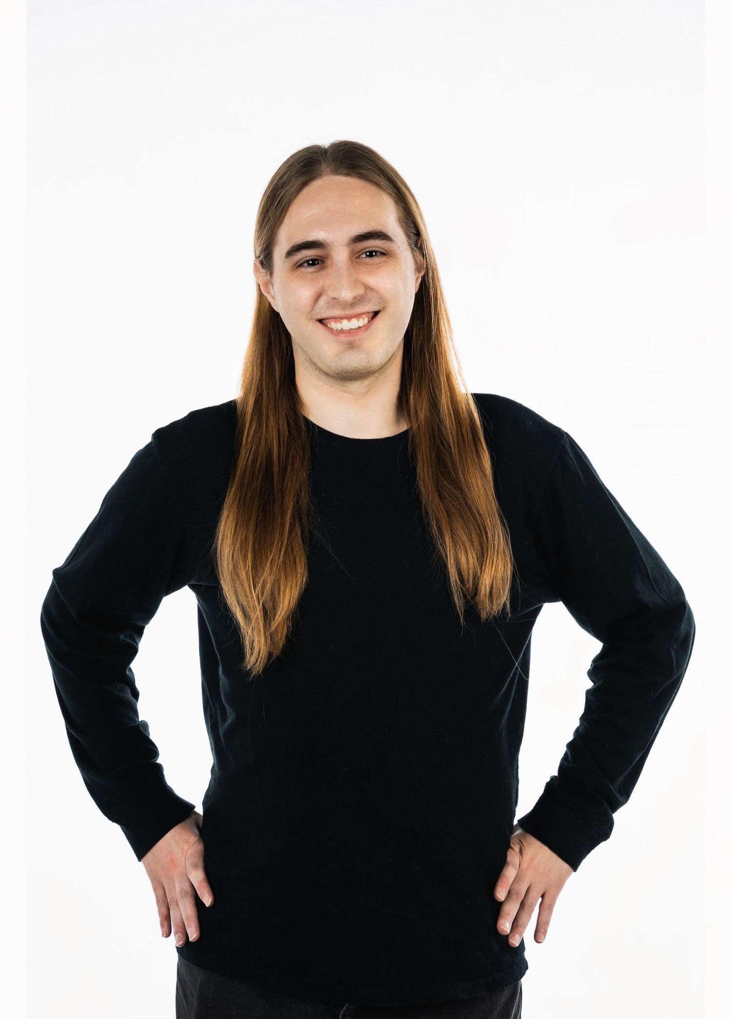 Portrait of person with long brown hair in black sweater against white background.
