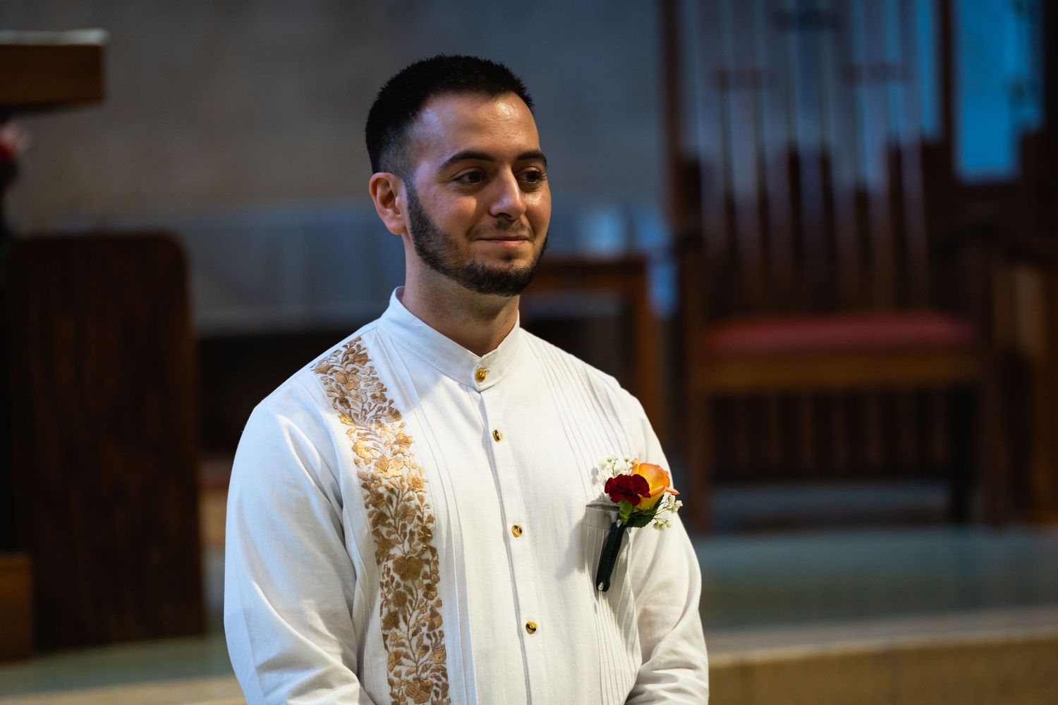 Wedding attendant wearing white formal attire with decorative gold vest and boutonniere.