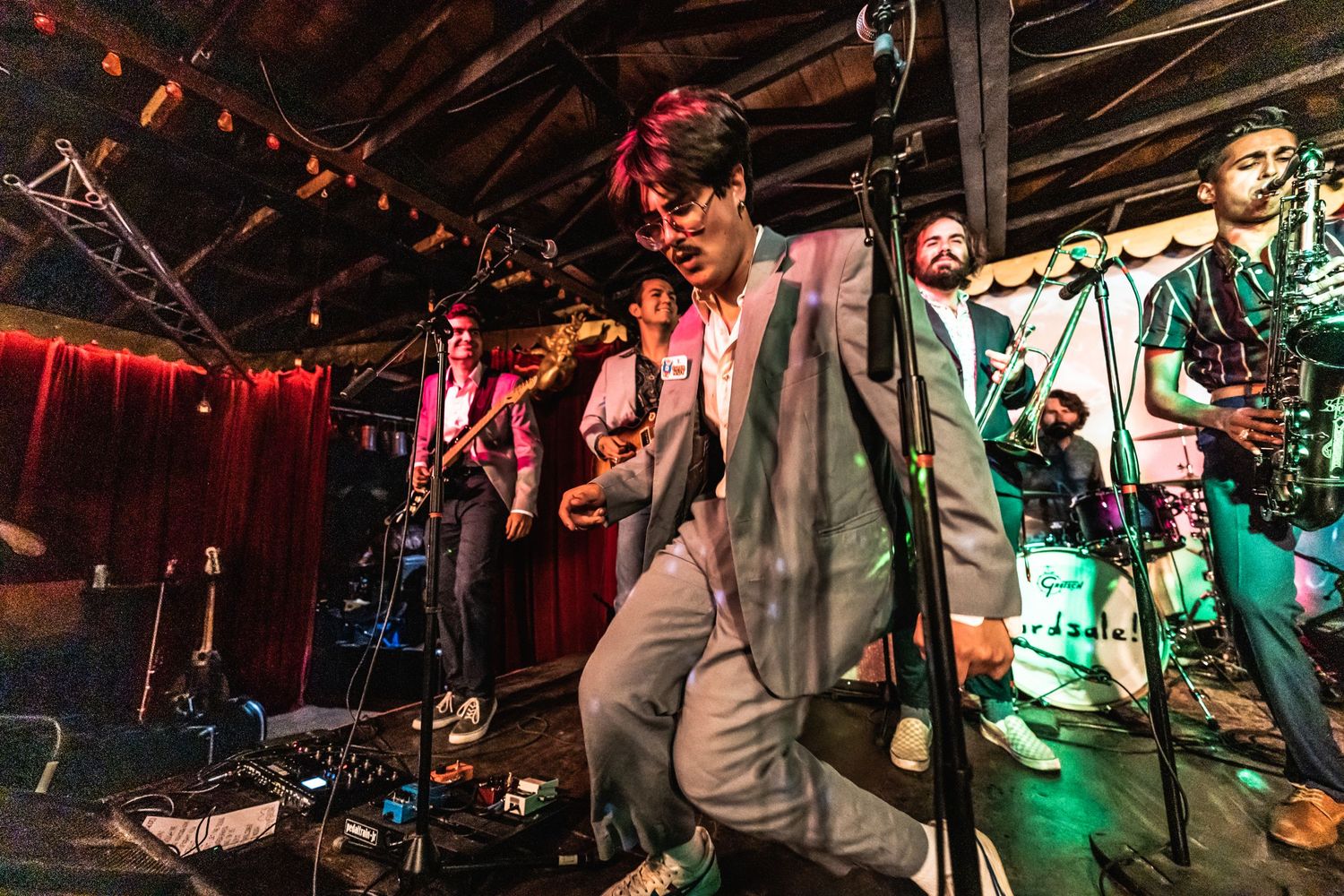 Live band performing on stage with colorful lighting and musical equipment.