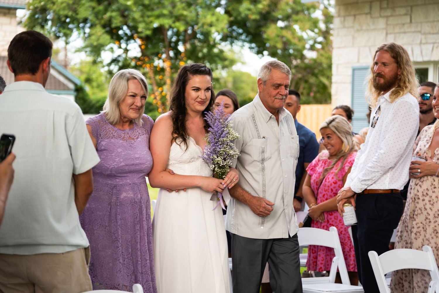 Candid moment from an outdoor wedding ceremony with guests in summer attire.
