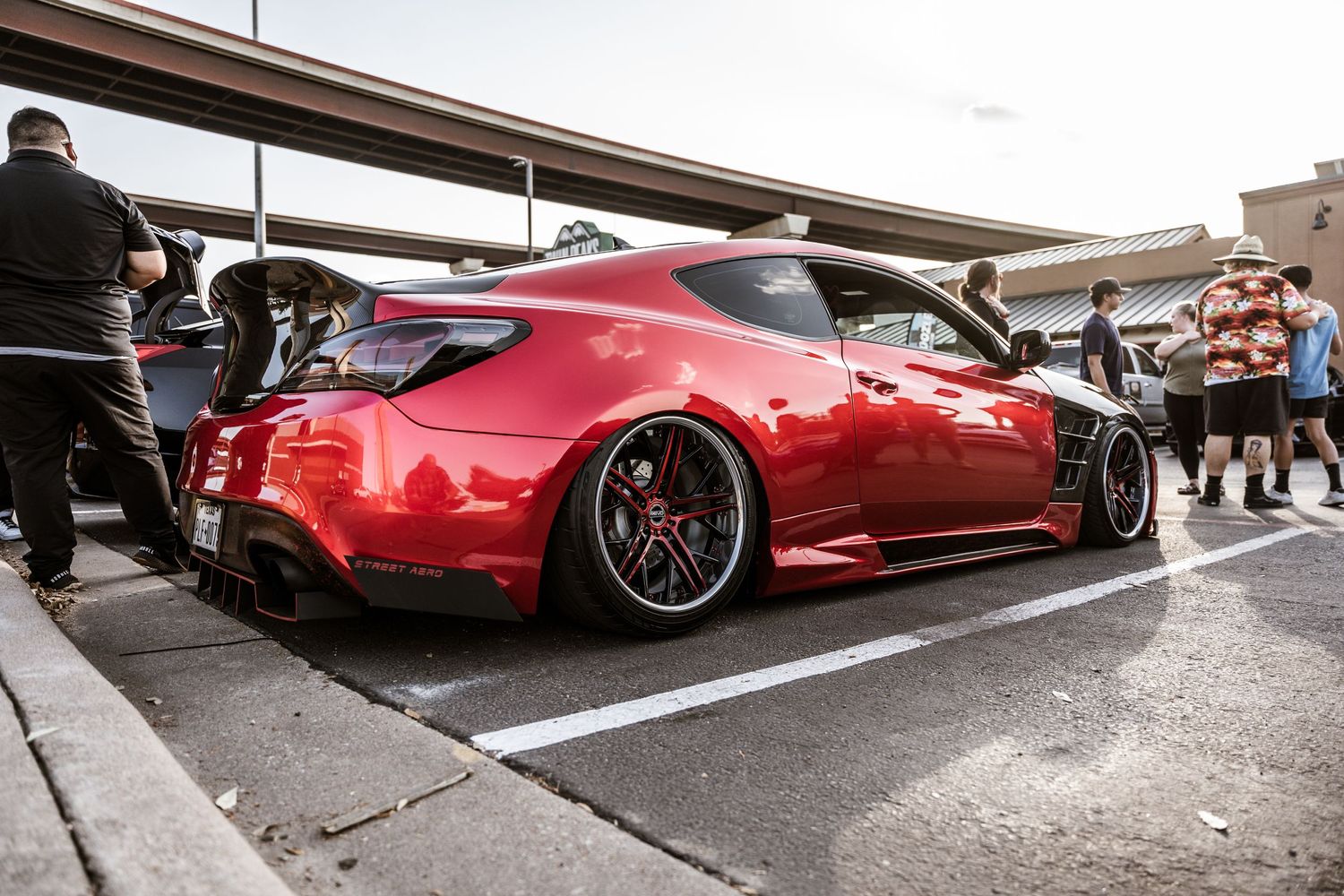 Lowered red Nissan Z sports car with custom wheels at a car meet.