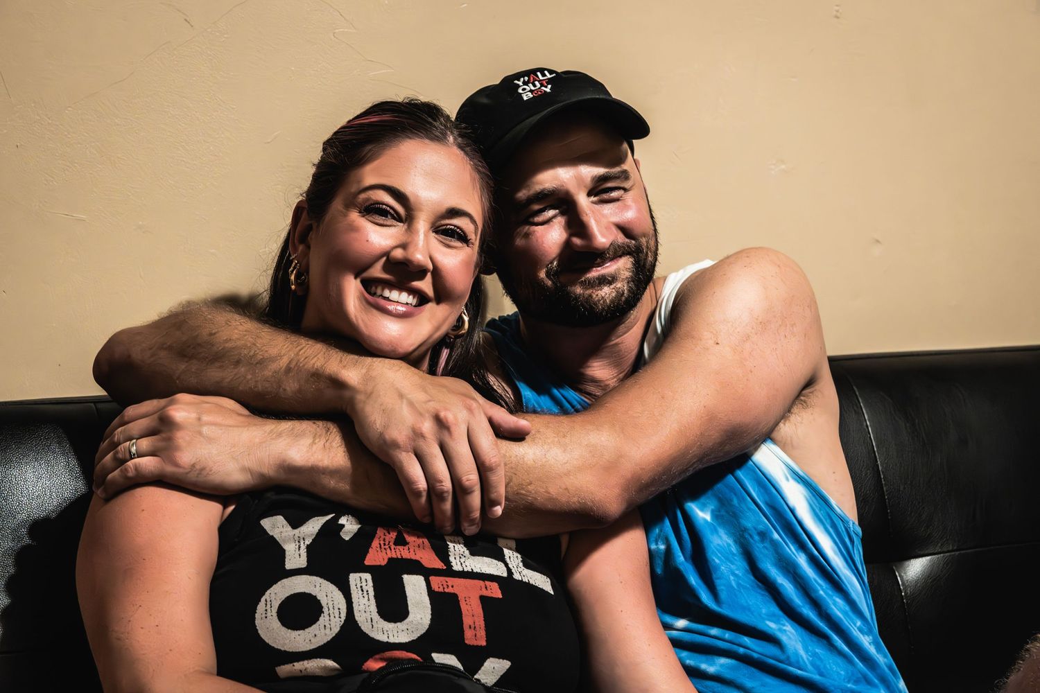 Two people sharing a happy moment on a black leather couch.