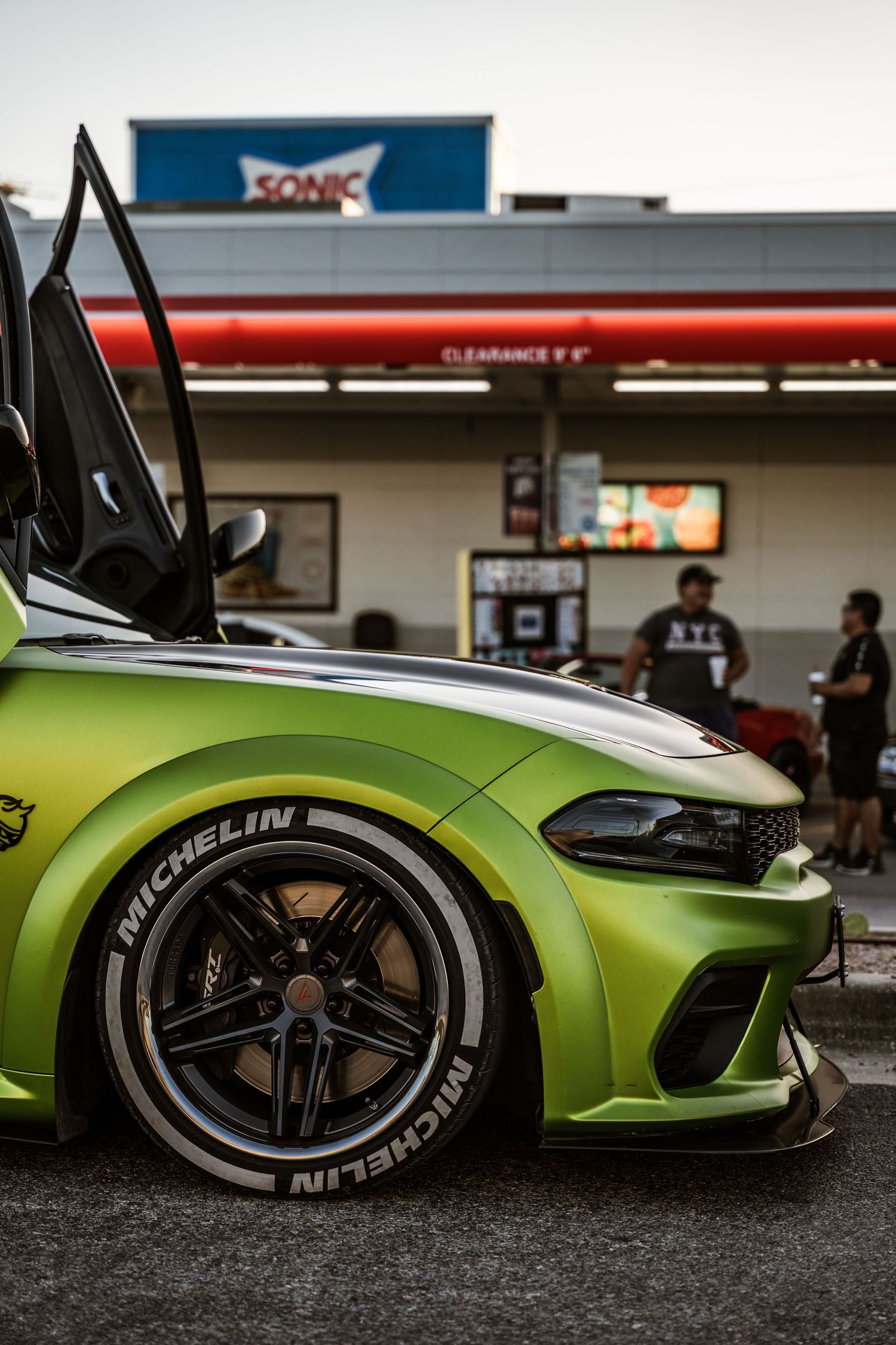 Close-up of a lime green Dodge Charger's custom wheel and side profile at a Sonic Drive-In.