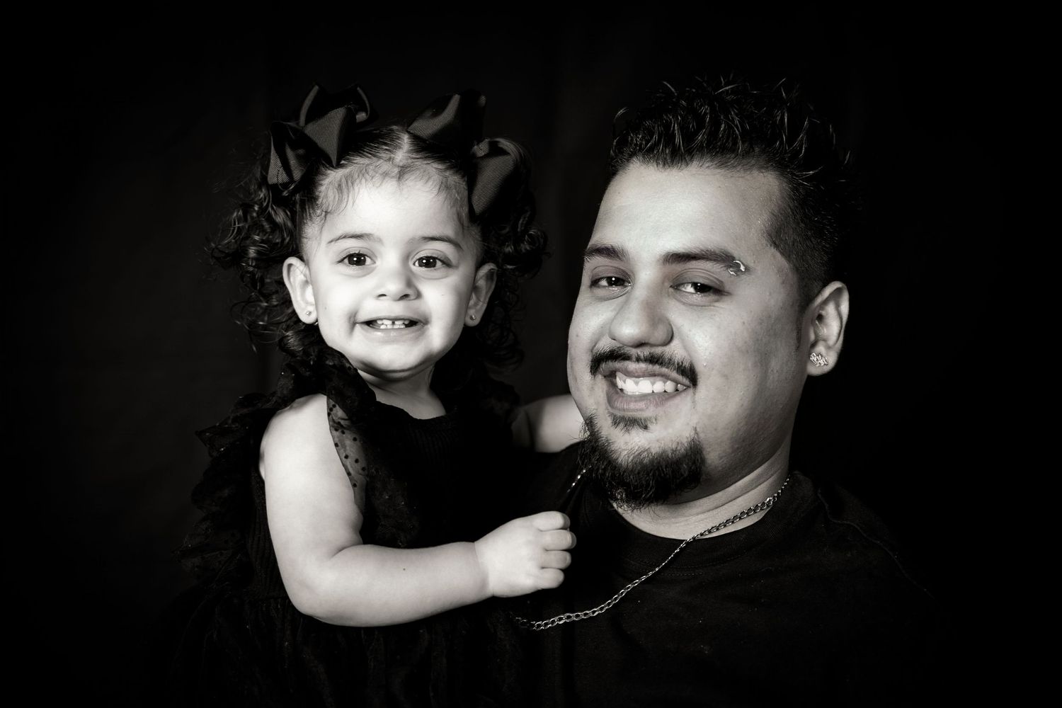 Playful black and white studio portrait showing parent and child laughing together.