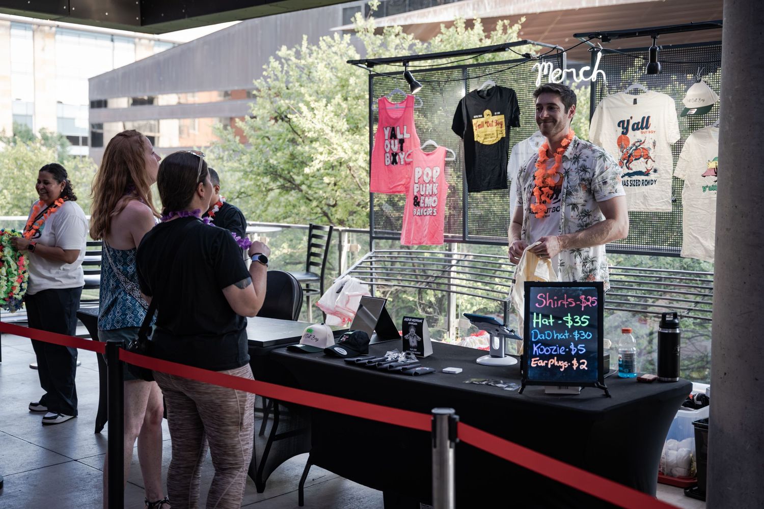 Vendor booth displaying graphic tees and merchandise with customers browsing at an outdoor market event.