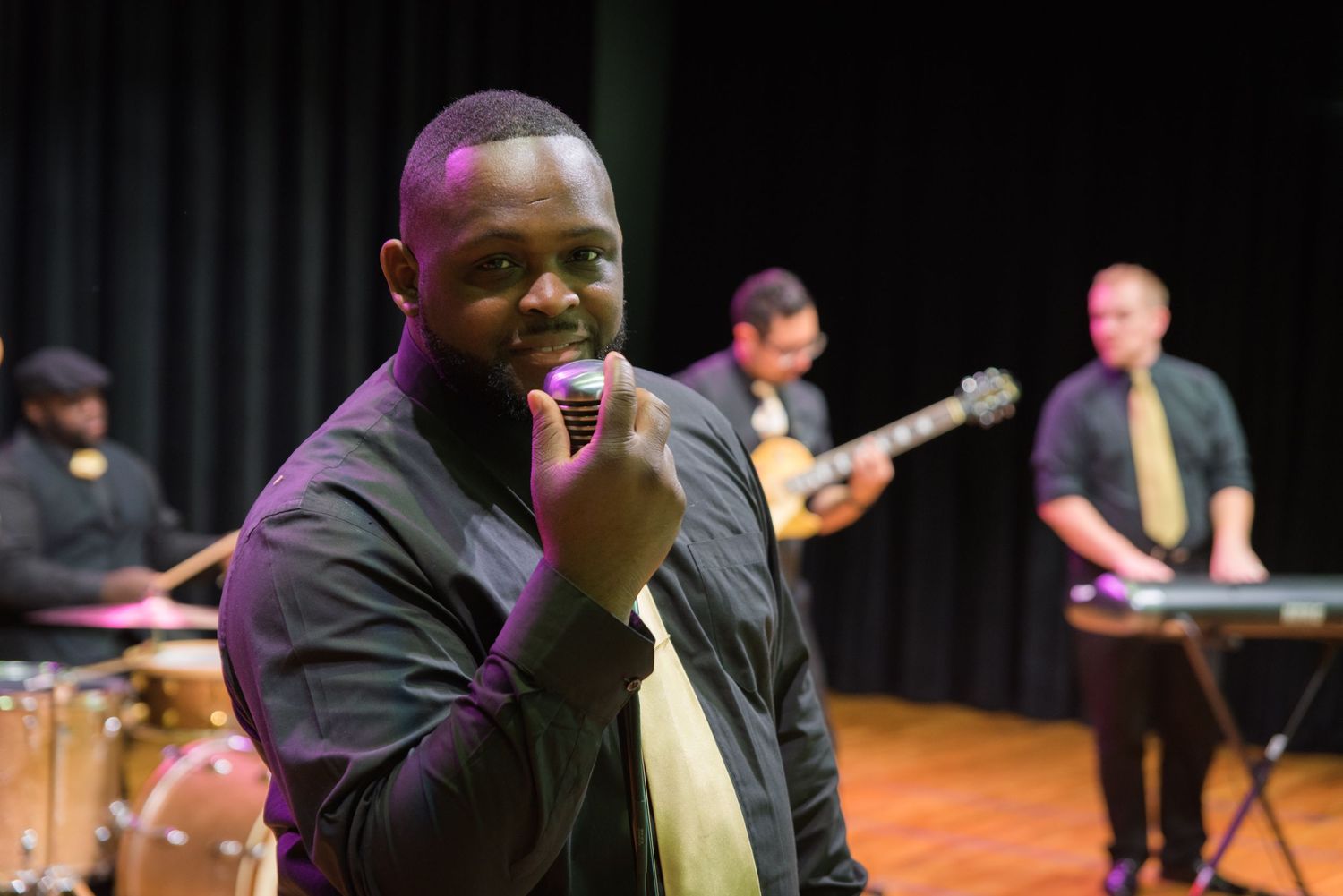 Musicians performing on stage during a jazz concert with piano, bass, drums and saxophone instruments.